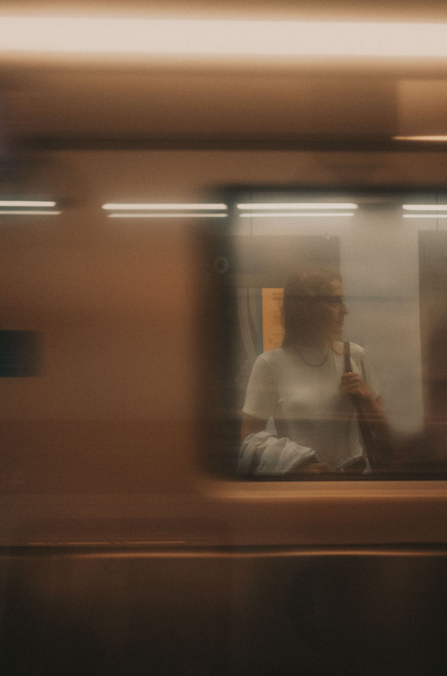 Moving subway train cars blur past the platform creating an abstract pattern of warm brown and orange tones.