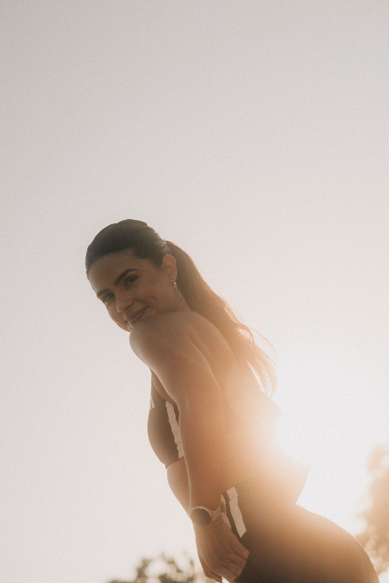 Low angle silhouette portrait shot with dramatic sunset light creating a warm rim glow effect in the background.
