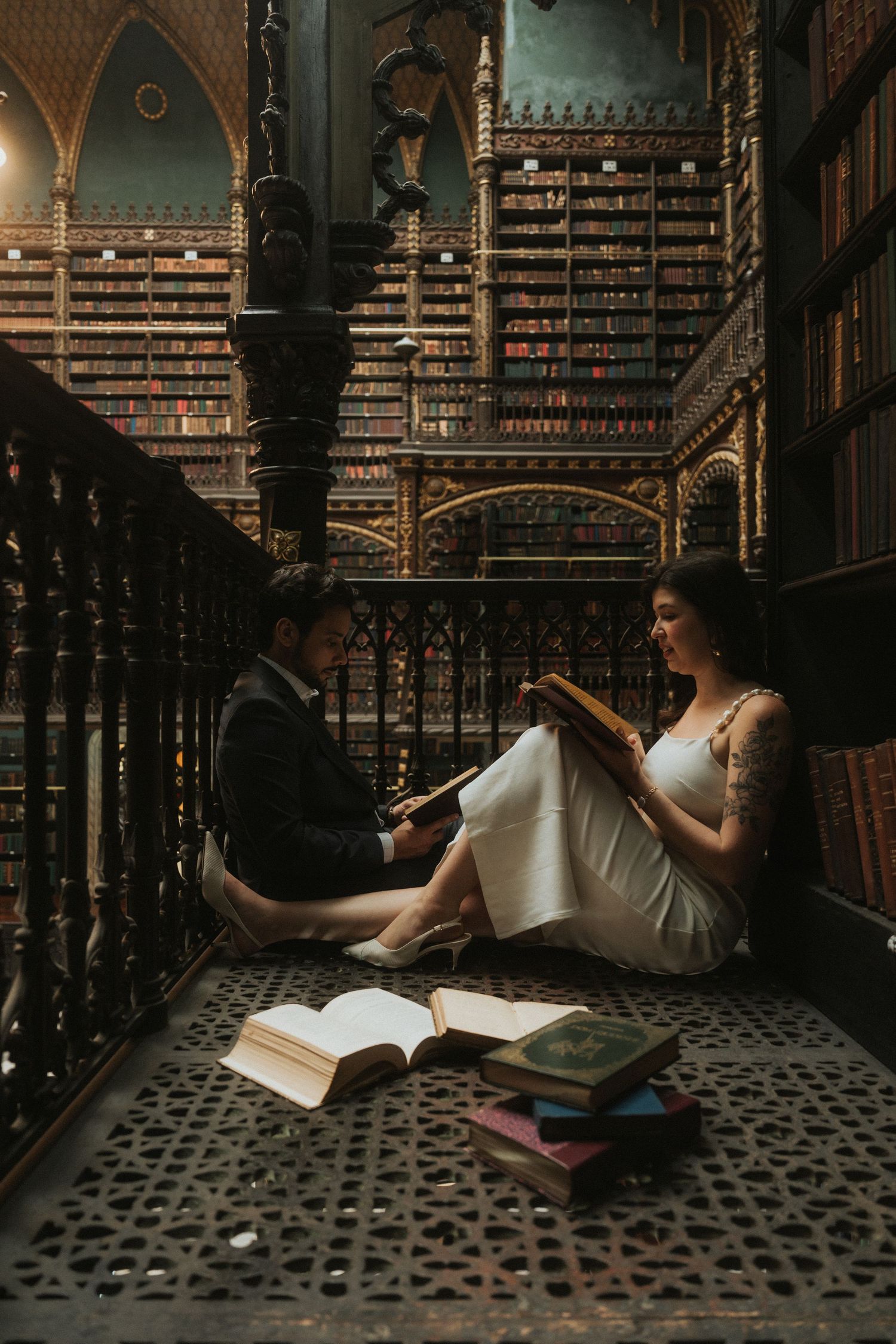 Artistic bridal portraits in vintage library with ornate iron railings and bookshelves.
