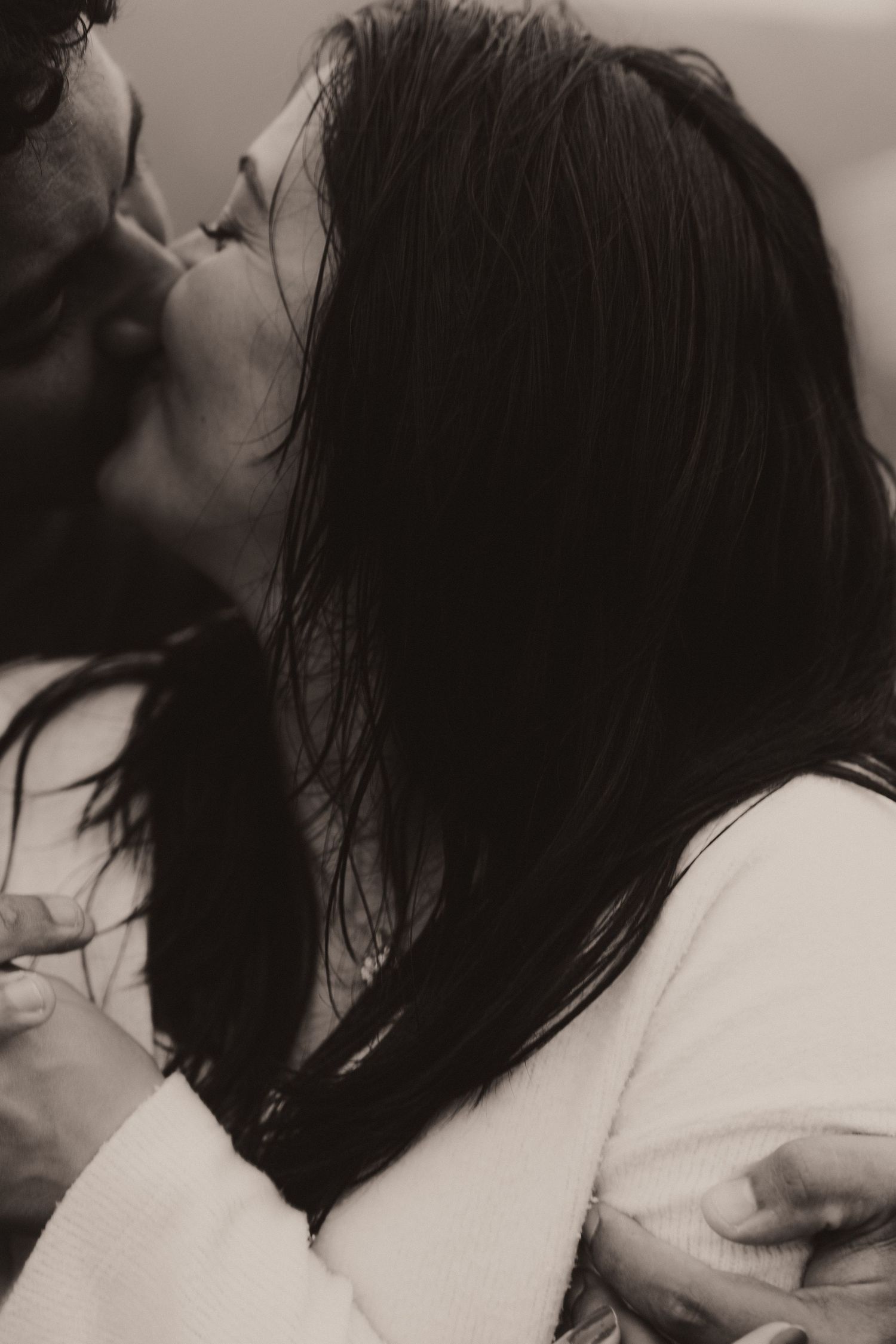 Black and white intimate portrait of a romantic couple embracing in soft lighting.