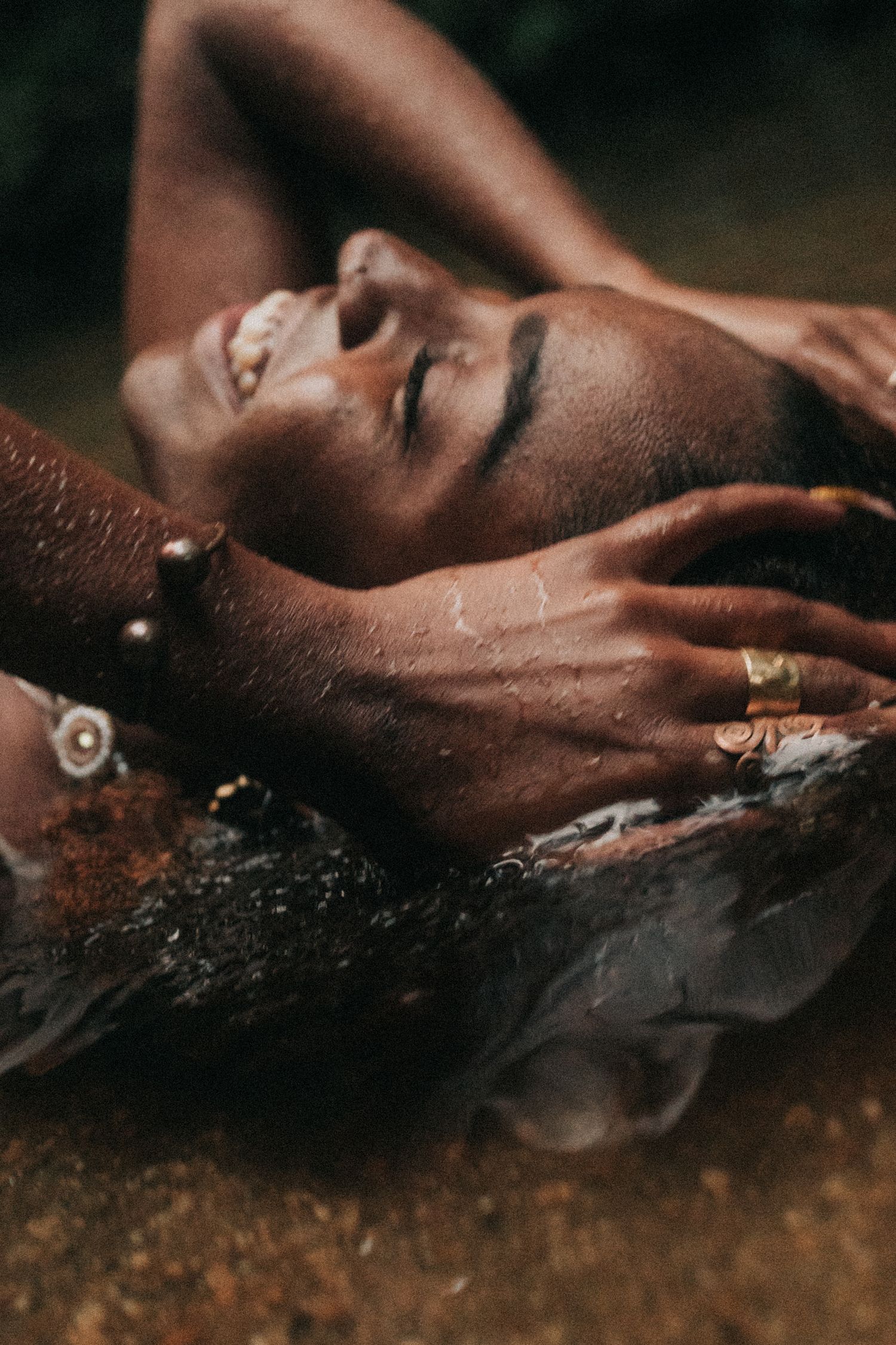 Close-up artistic portrait series showing dark skin with water droplets in dramatic lighting.