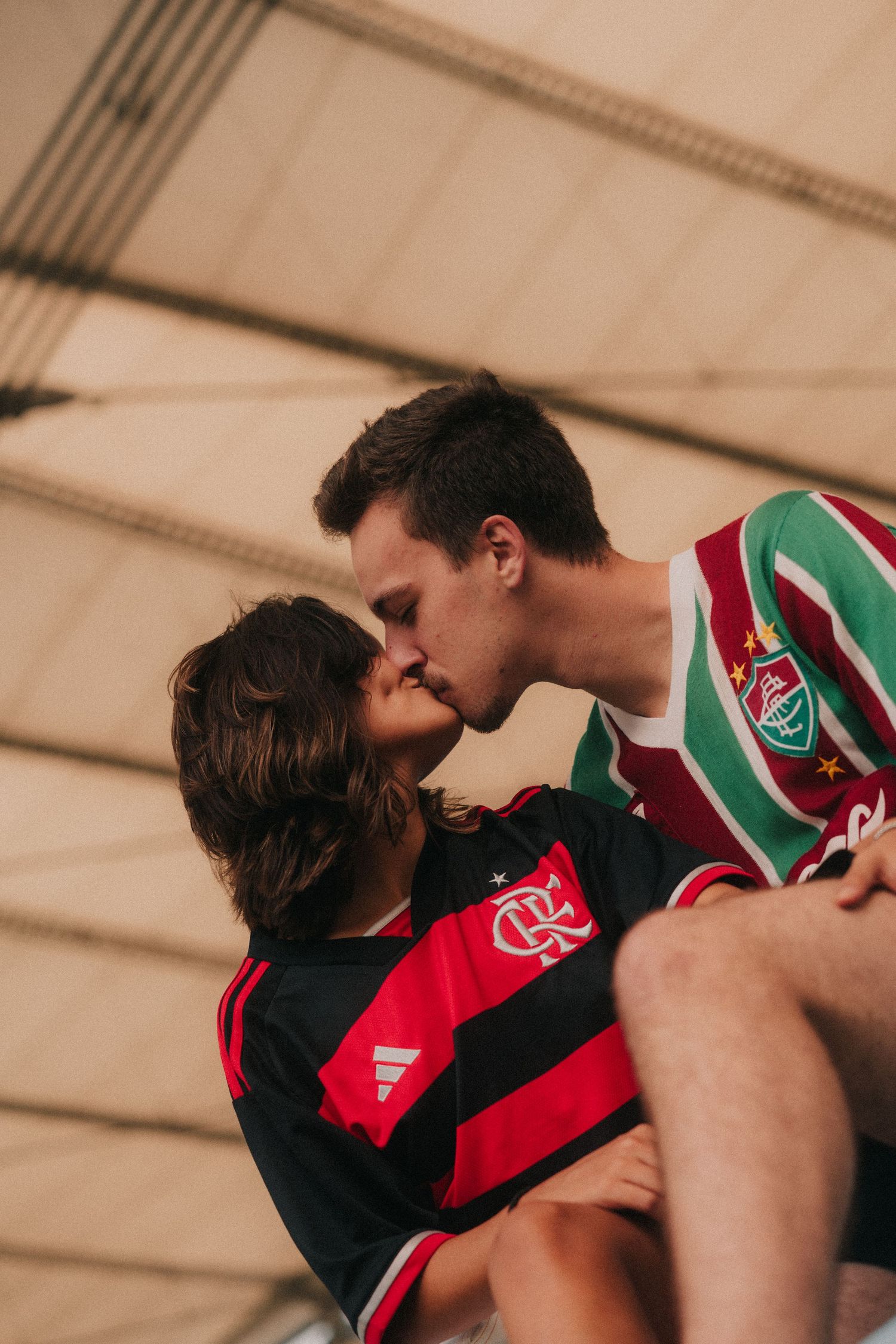 Two players in red and green striped jerseys engage in an intense rugby match collision.