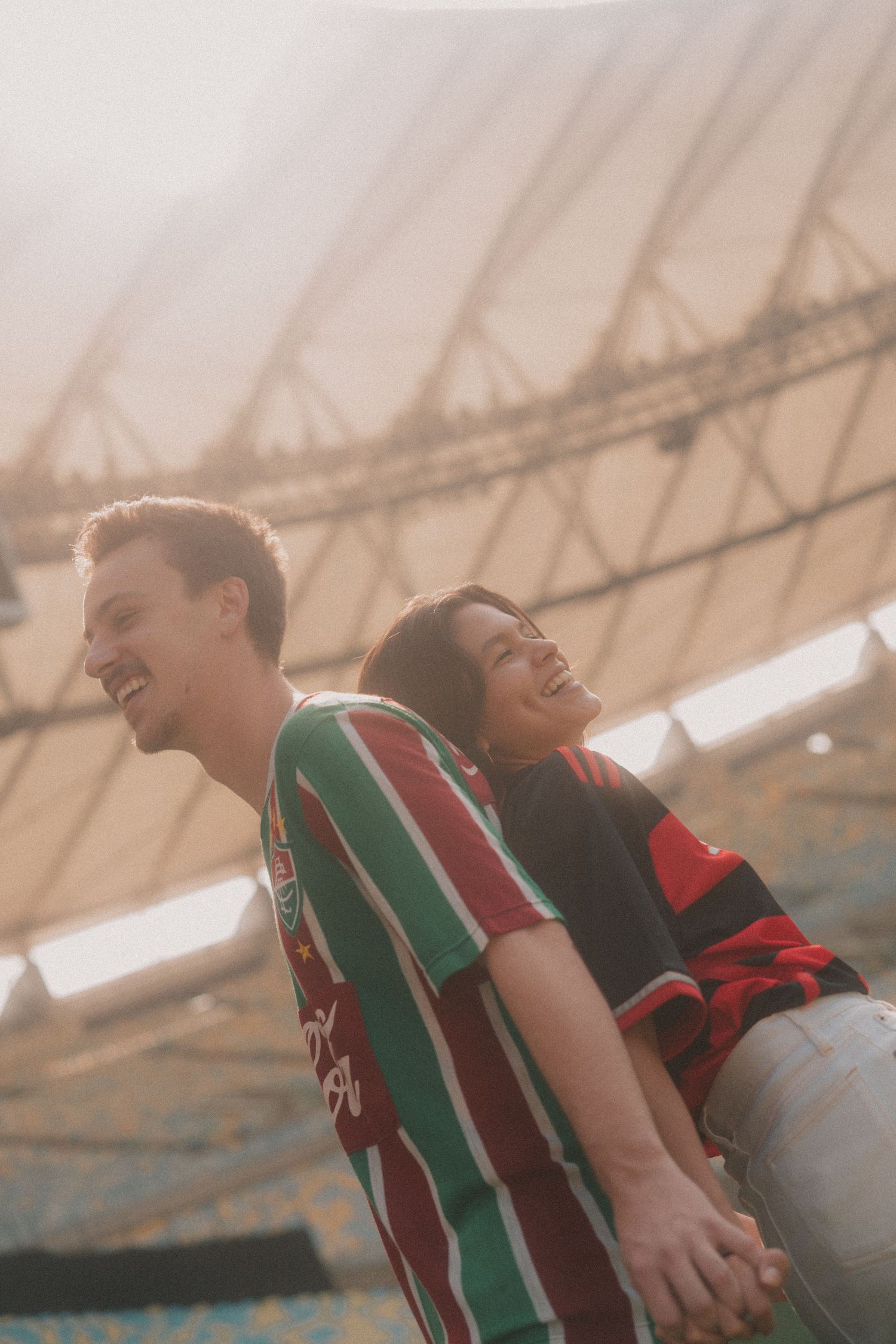 Two soccer players in green and red jerseys celebrate joyfully together on the field.