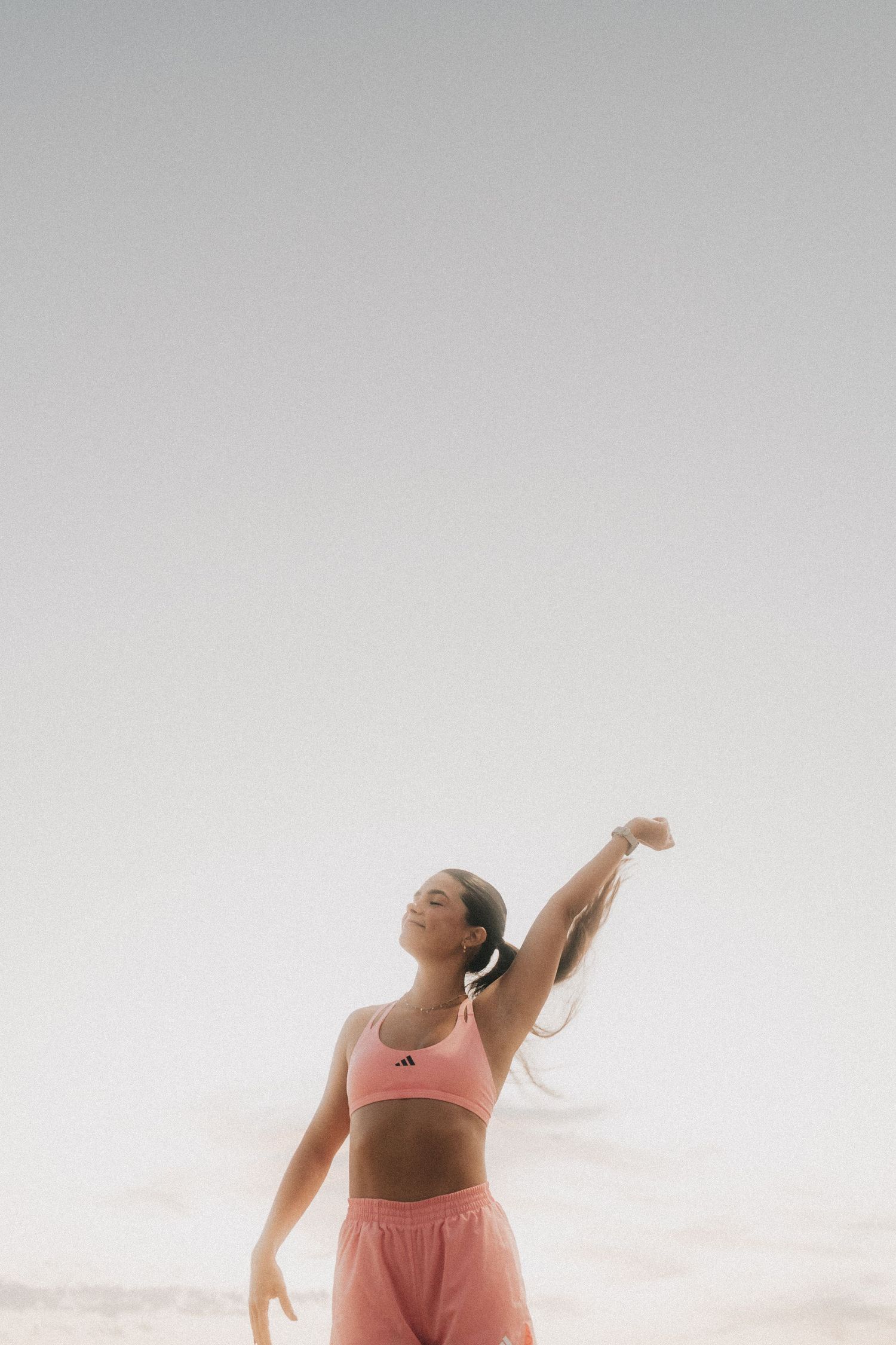 Woman in pink activewear practicing yoga poses outdoors during sunset with dreamy atmospheric lighting.