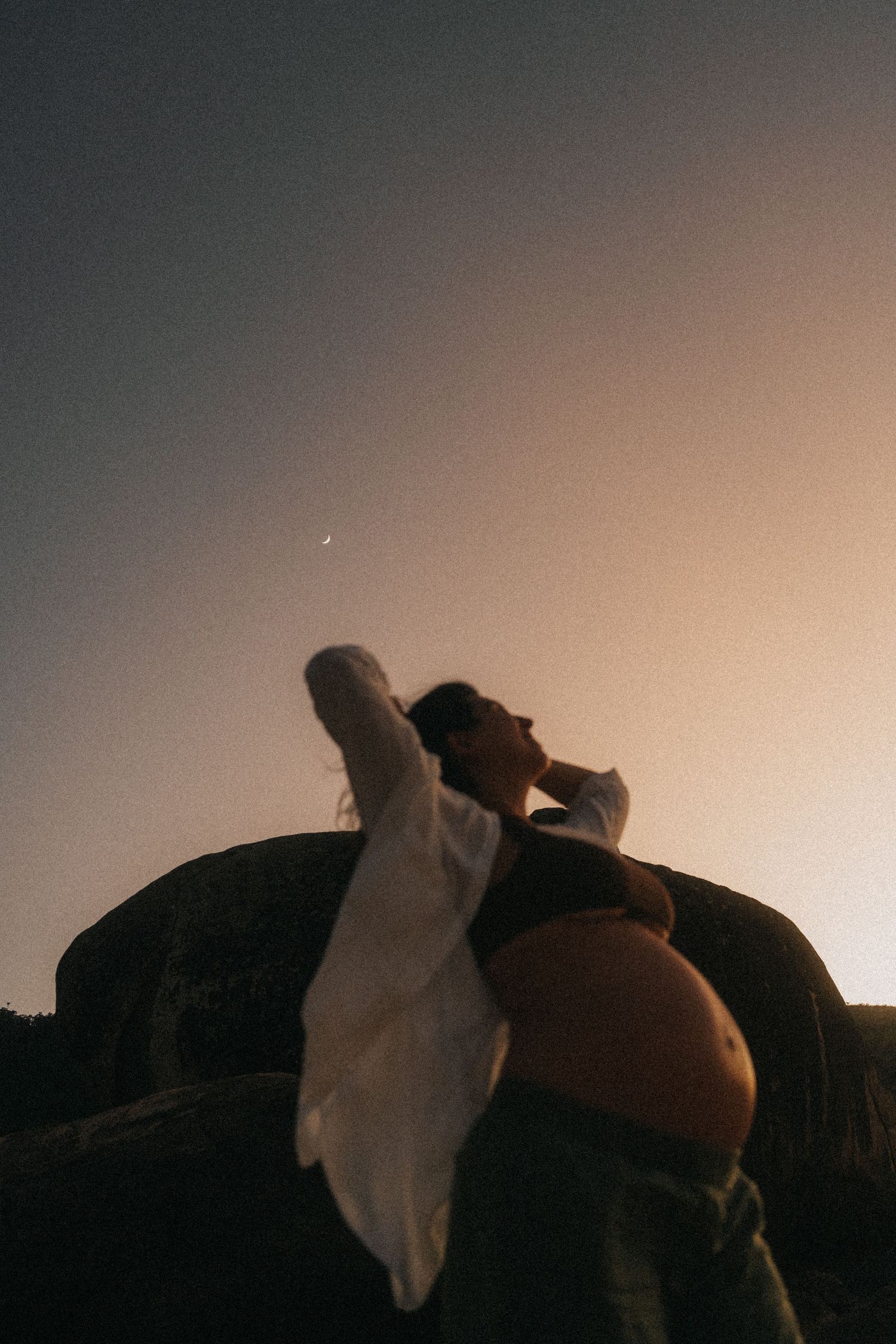 A silhouetted figure against a sunset sky wearing flowing white fabric.