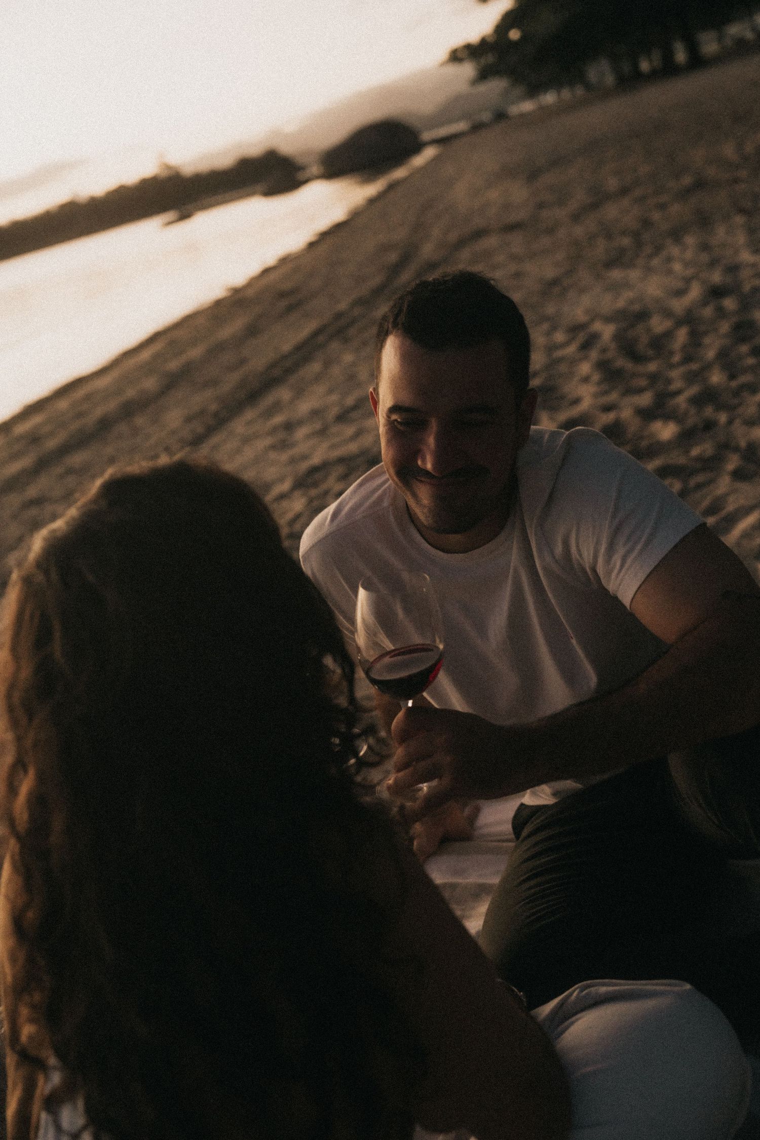Two people share an intimate moment on a beach during sunset, creating a romantic silhouette against the dusky sky.