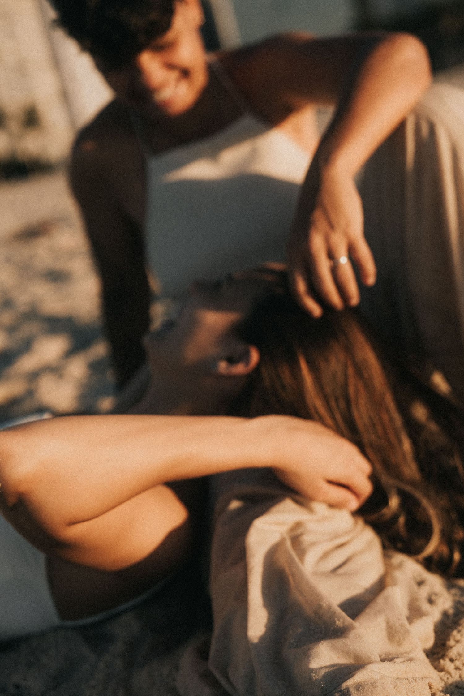 A series of close-up shots showing hands gently touching light fabric in warm evening sunlight.