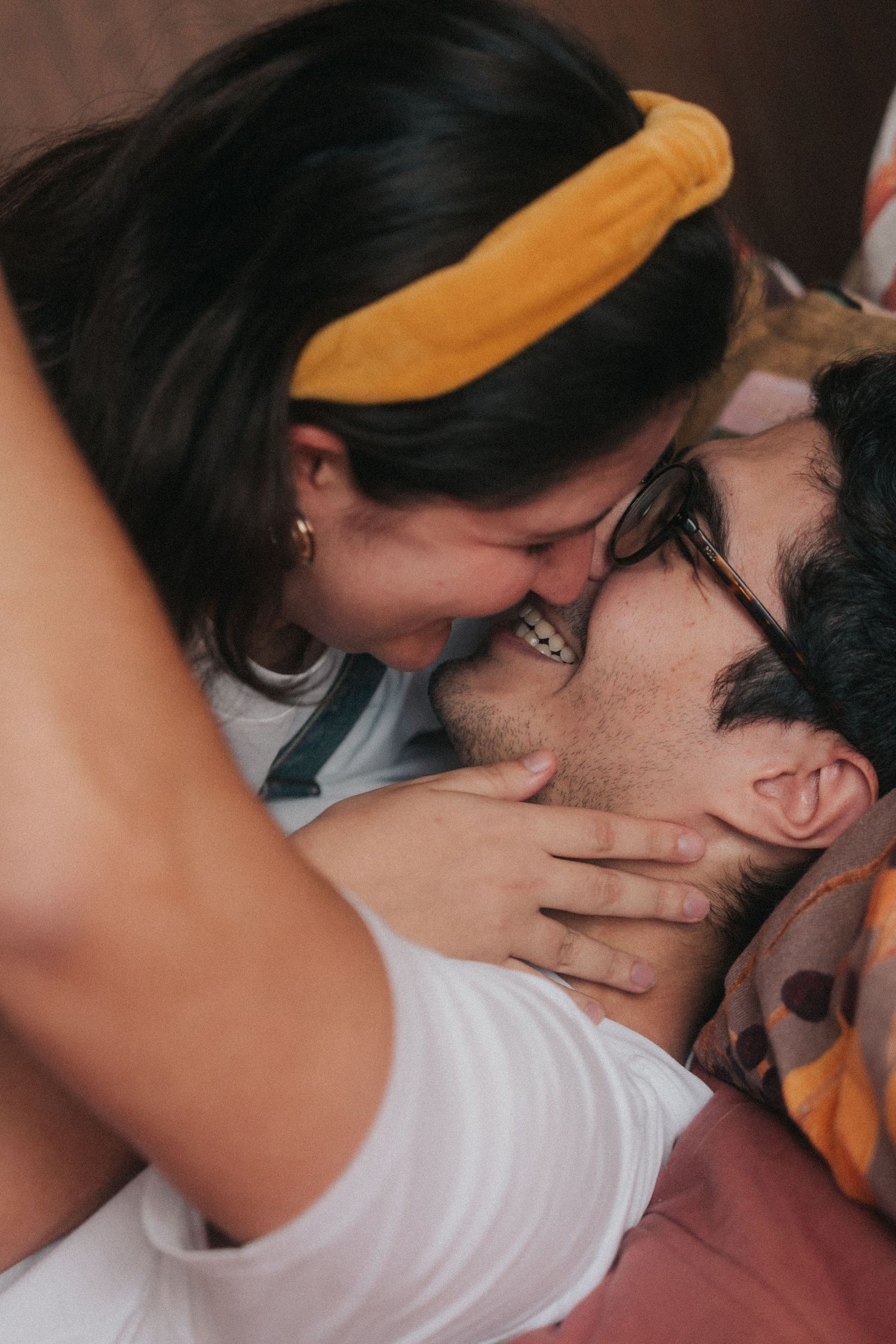 Intimate couple sharing a tender kiss while wearing a yellow headband and white t-shirt.