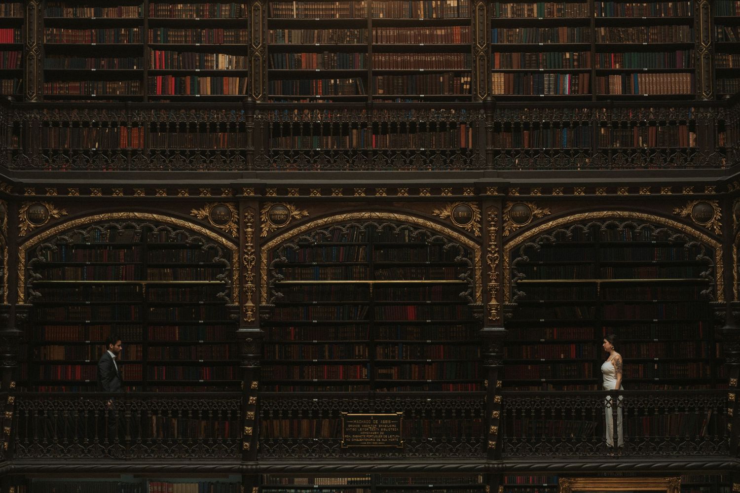 Ornate wooden bookshelves filled with antique leather-bound books line the walls of a historic library interior.