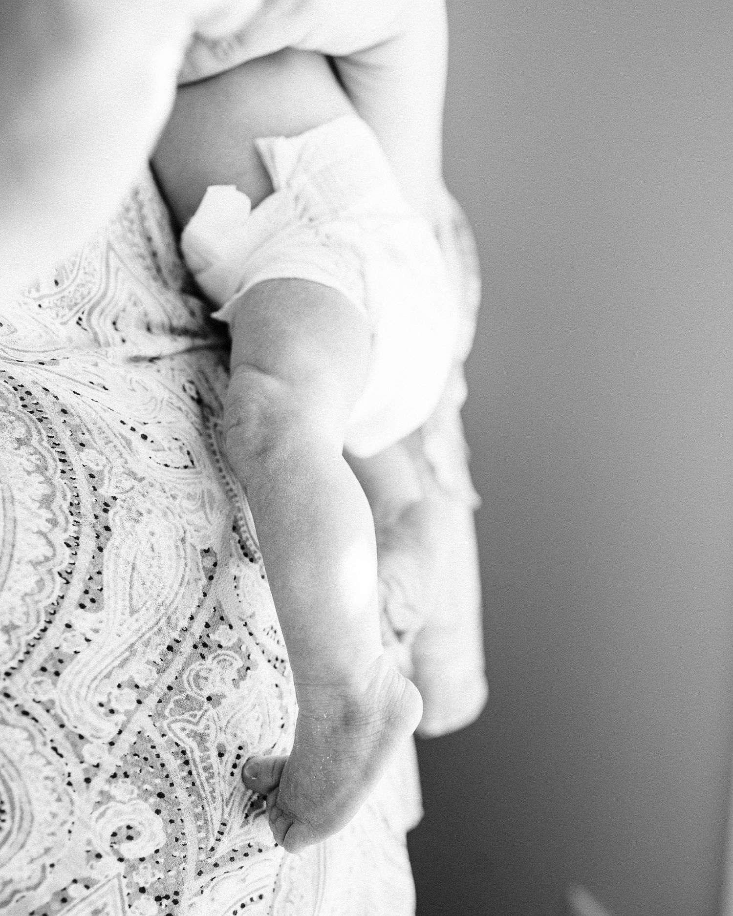 Black and white artistic detail shot of baby's tiny feet against lace fabric.