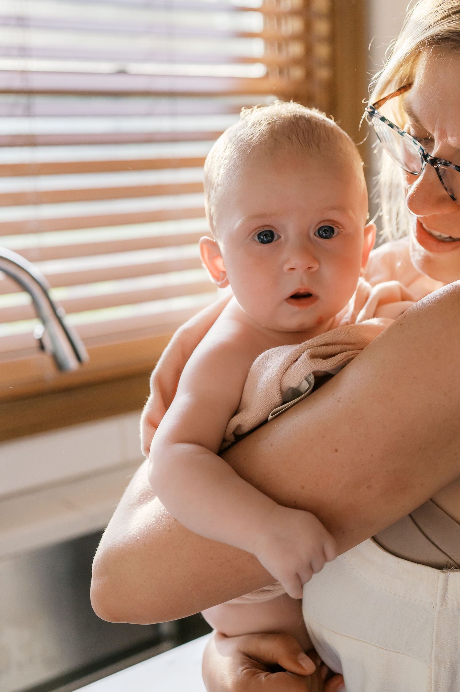 Sweet moment by the kitchen sink as a baby gazes with bright eyes.