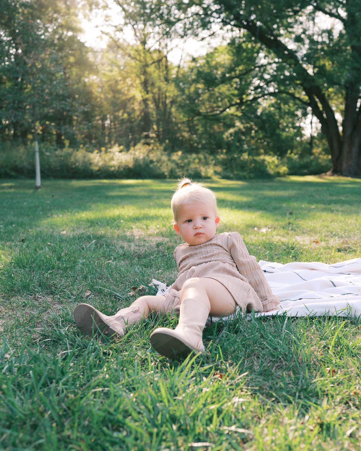 Baby crawling on grass in a sunlit garden during a warm autumn day.