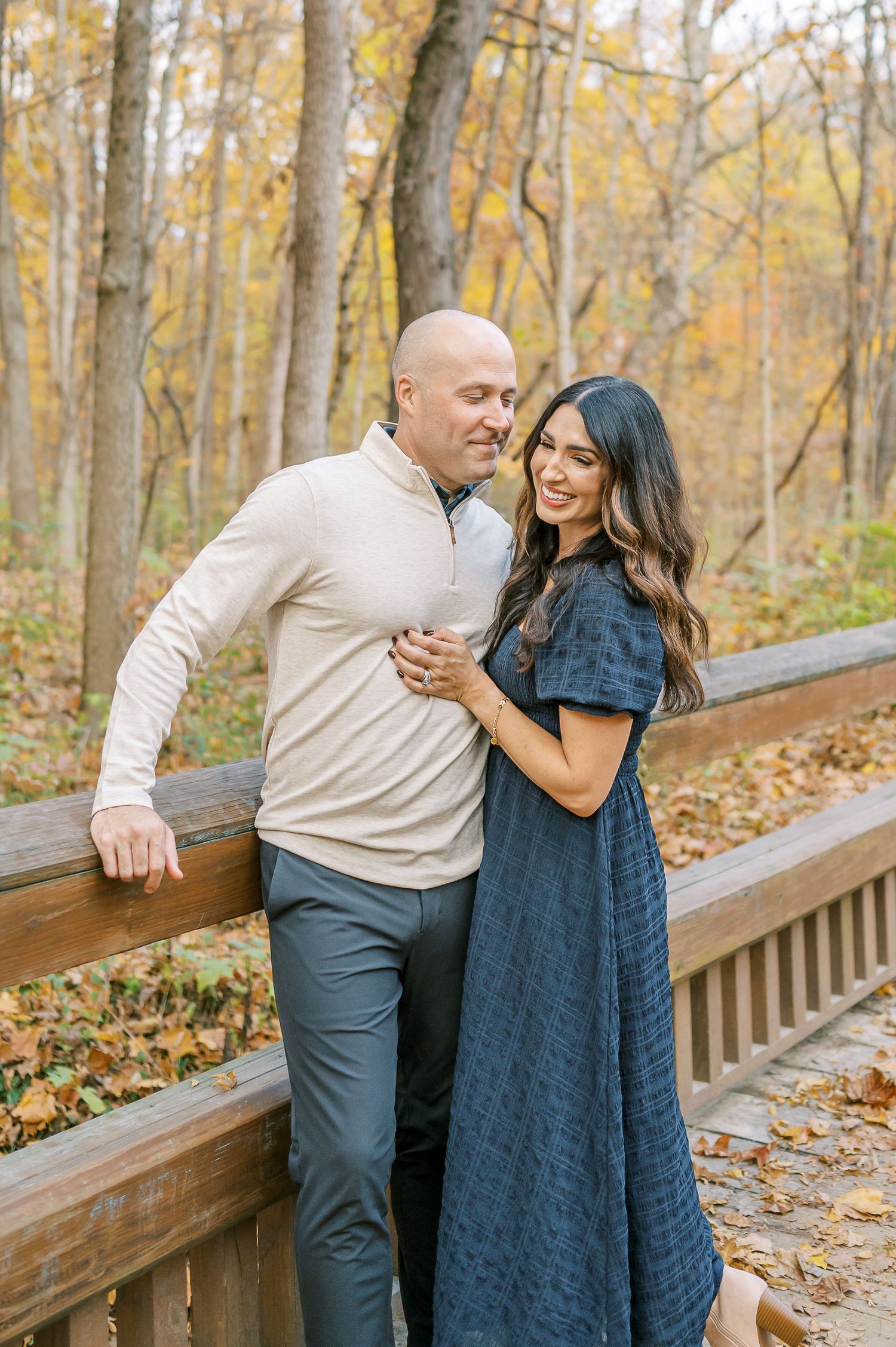 Couple sharing tender moments while walking along autumn boardwalk trail.
