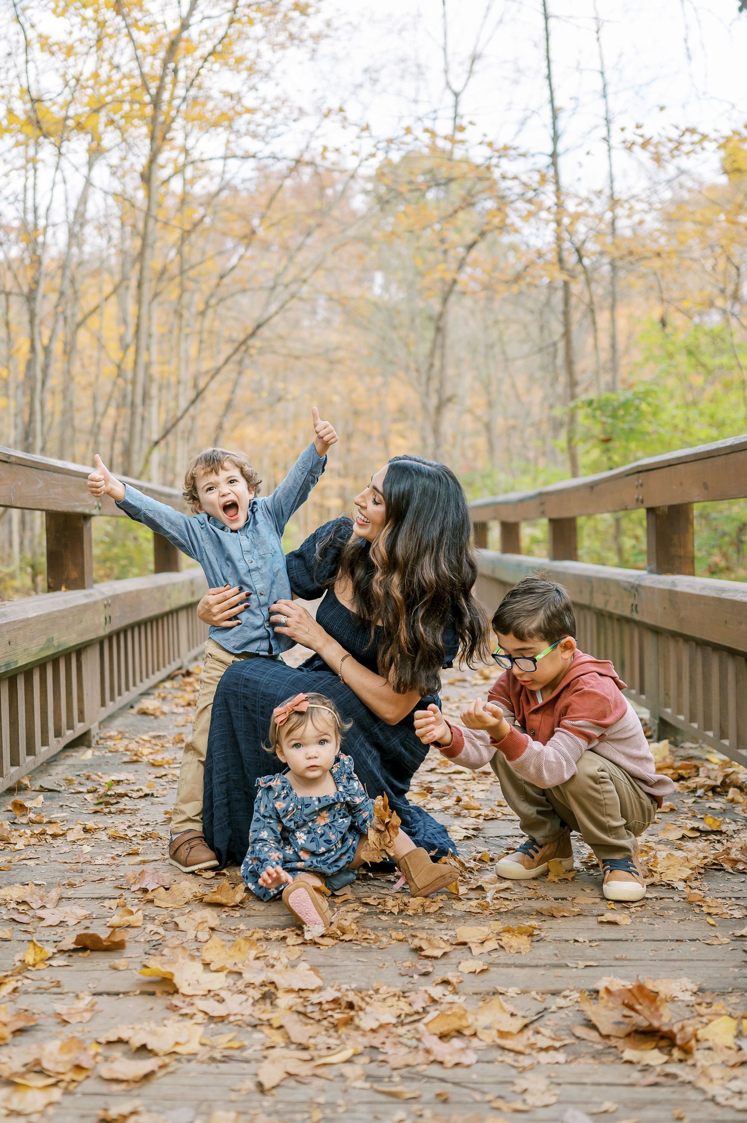 Candid moments of family playtime on a trail covered in golden fall leaves.