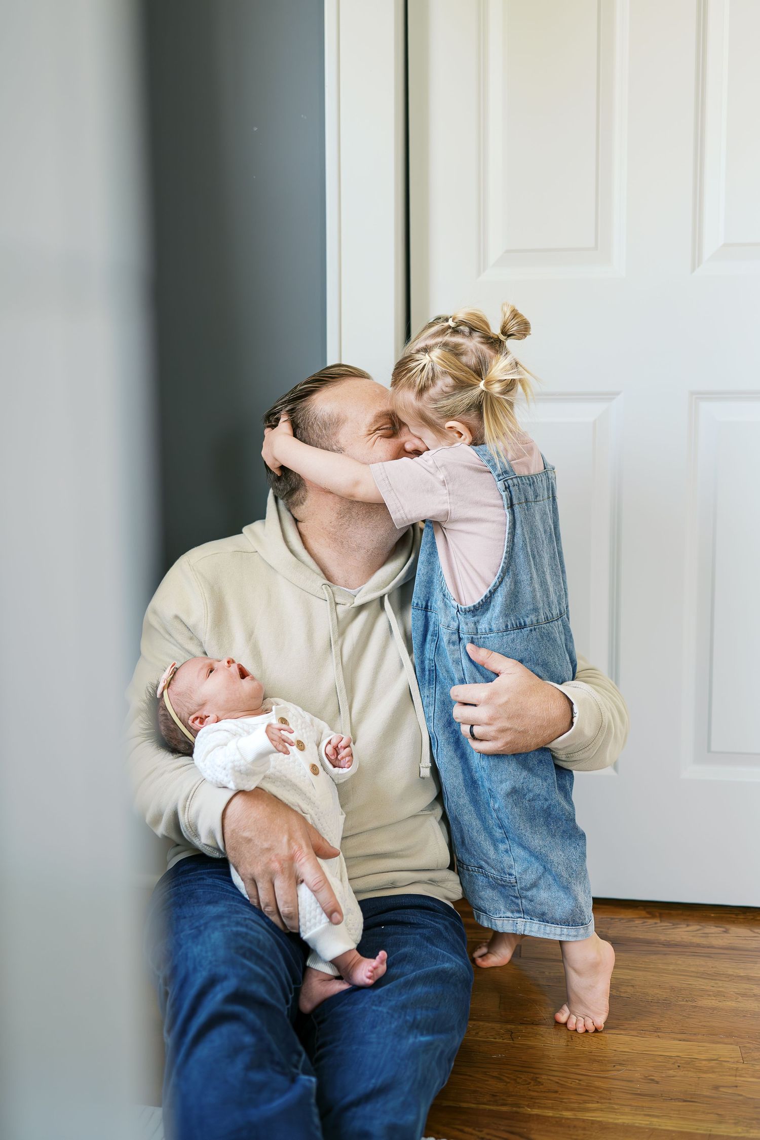 A sweet family interaction captured near a white door in natural lighting.