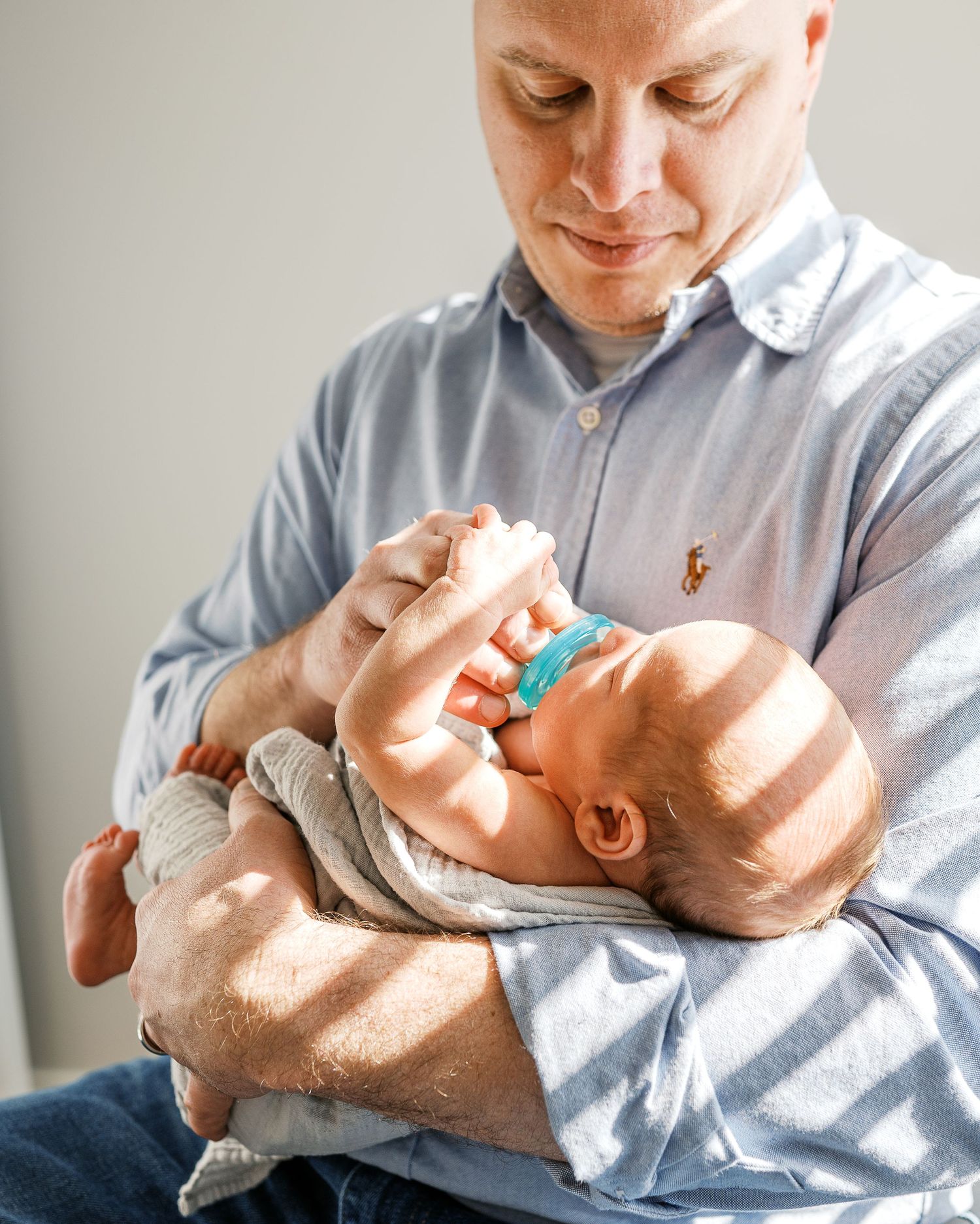 Series of tender moments as parent cradles sleeping newborn baby.