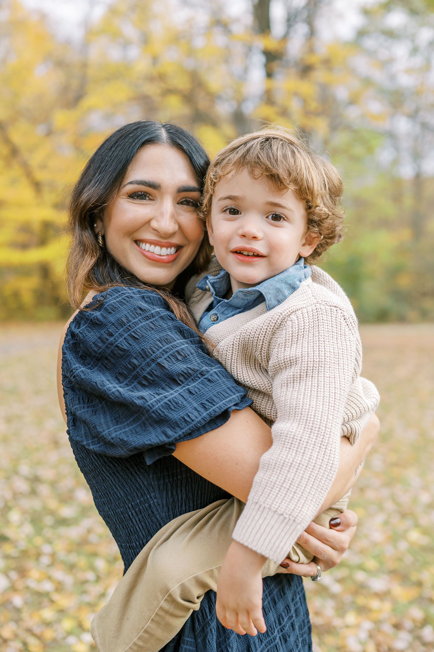 Warm embrace shared between parent and child against backdrop of golden autumn trees.