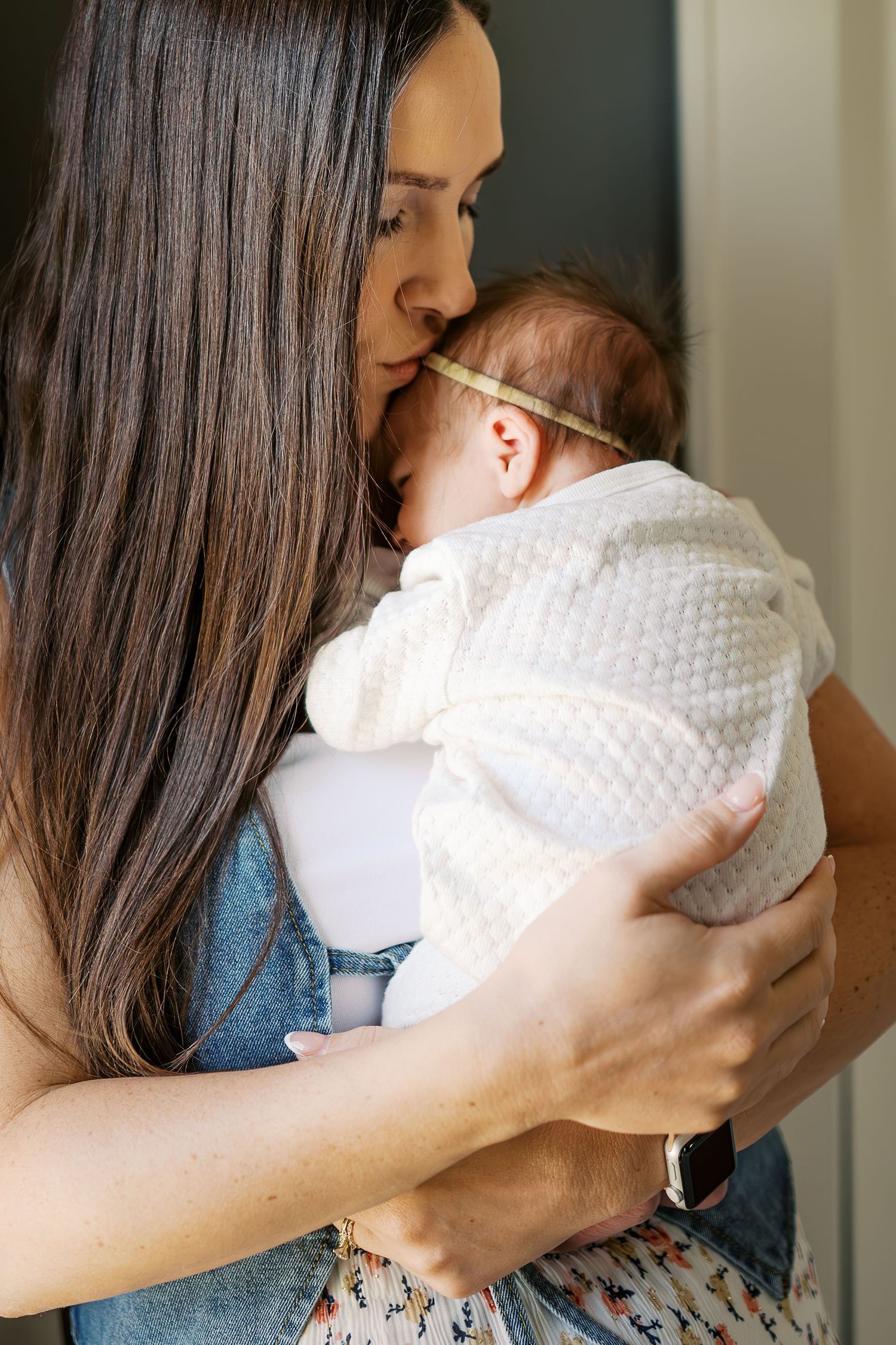 Tender moment with a baby in white being held close and gently embraced.