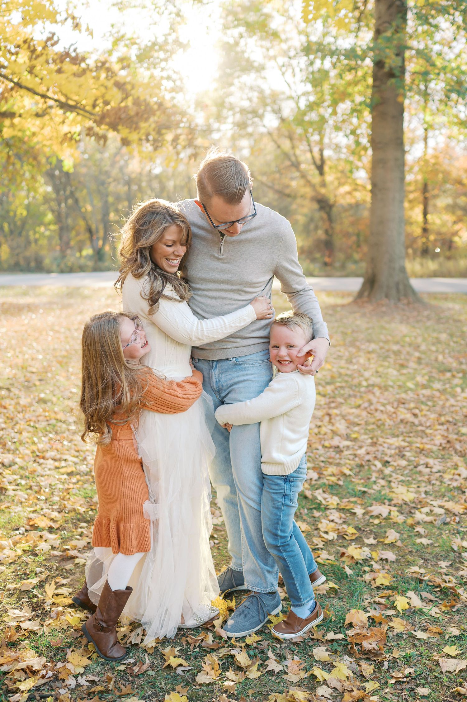 Playful family interaction on fallen leaves during an autumn photo session.