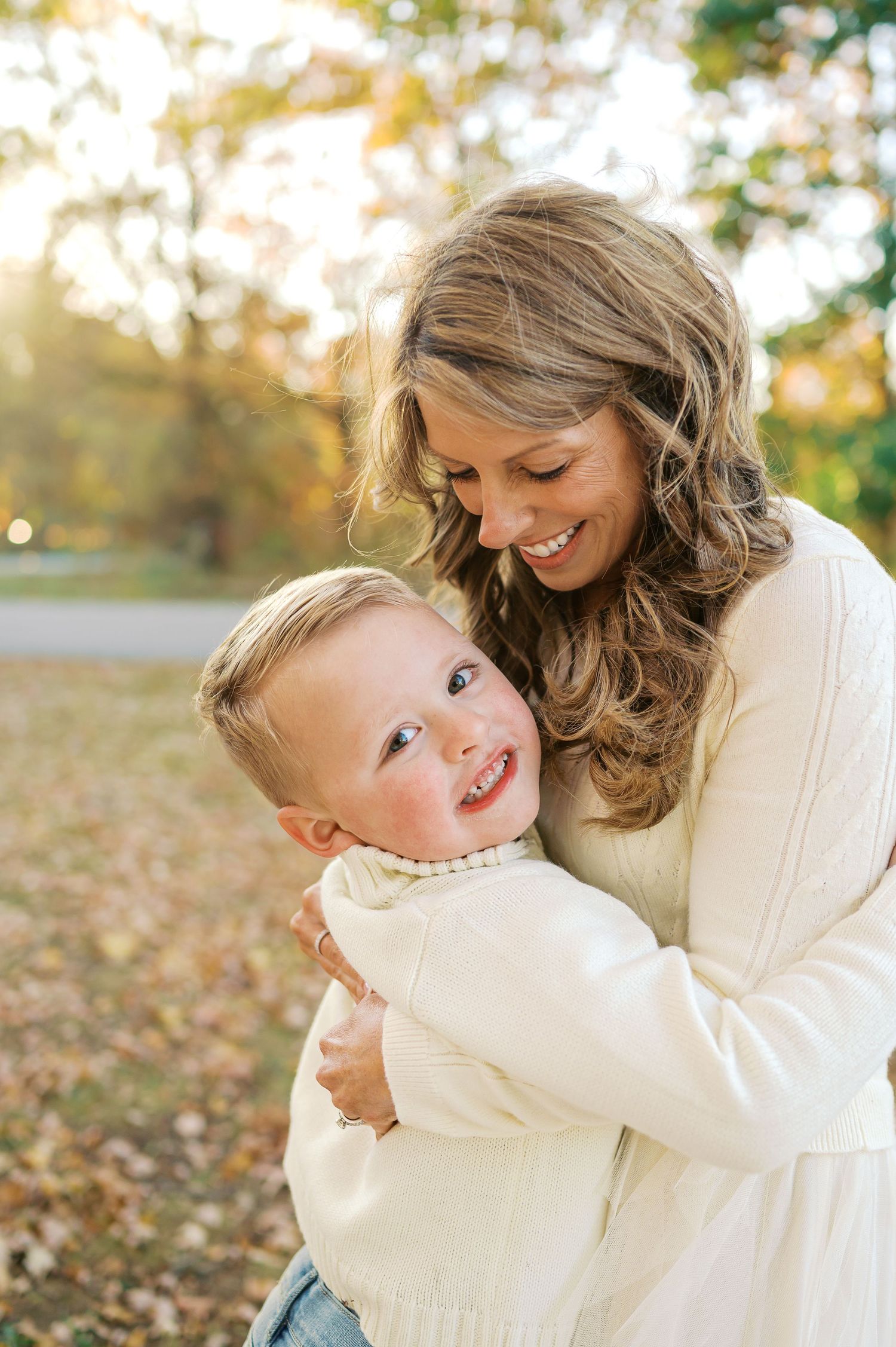 Candid embrace between parent and child wearing matching cream sweaters in fall setting.
