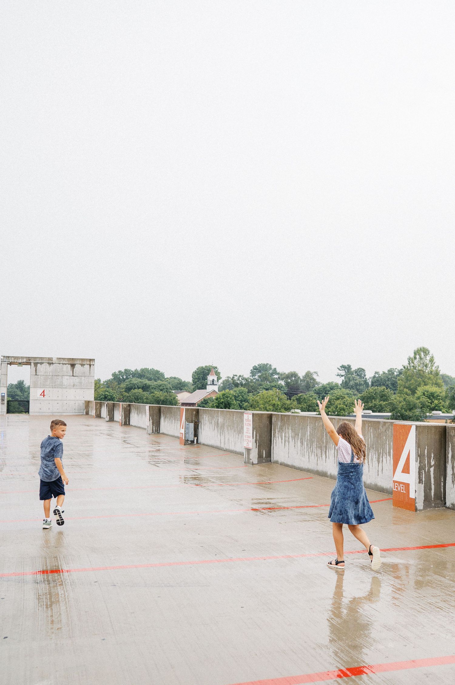 Family playing on wet ground with puddles at sunset.