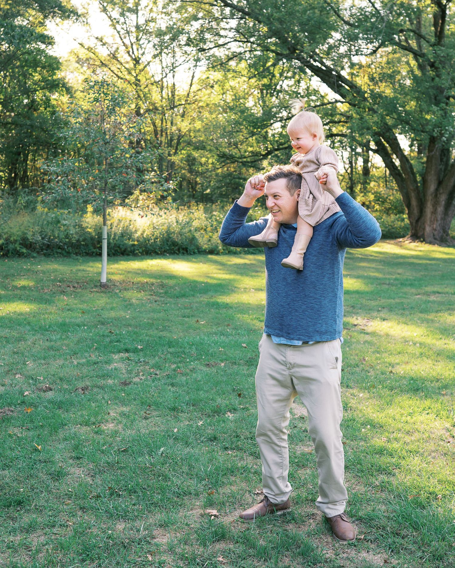A playful outdoor scene in a grassy park with trees during golden hour sunlight.