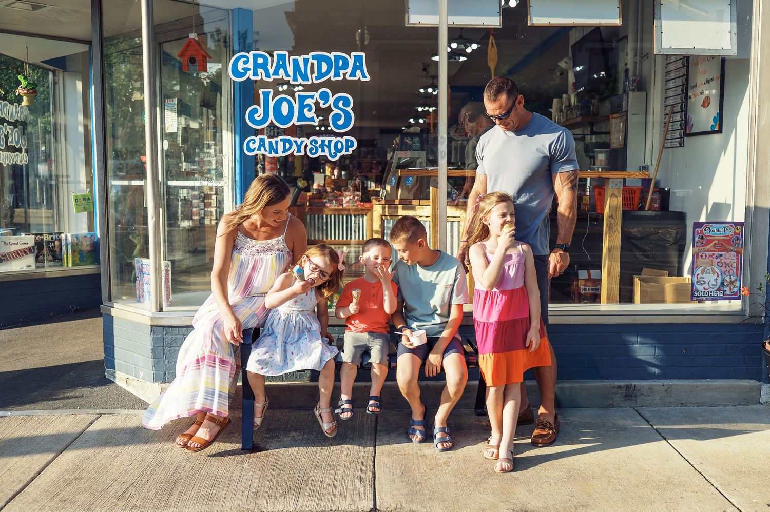 People gathered outside an ice cream shop storefront on a sunny day.