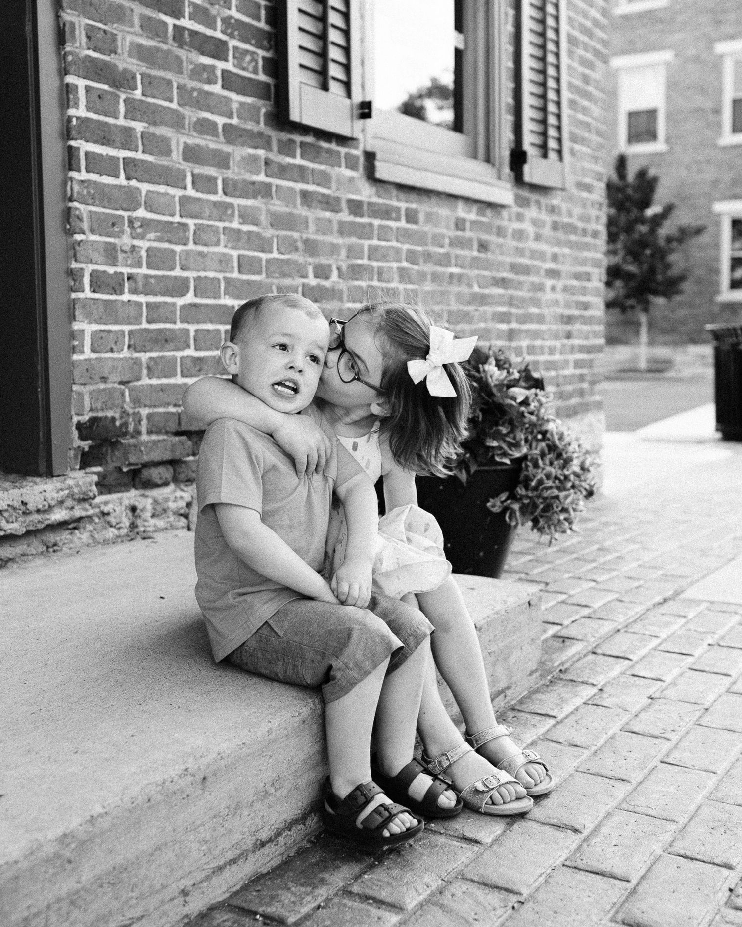 Black and white image of children sitting on brick steps in playful poses.