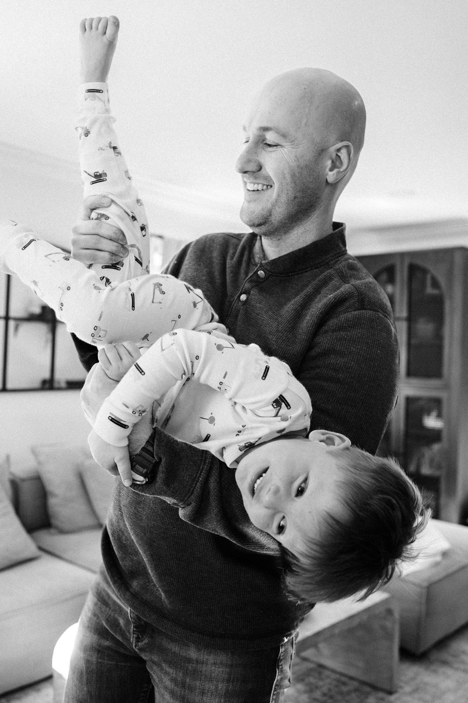 Black and white photos capture intimate family playtime moments in a home setting.