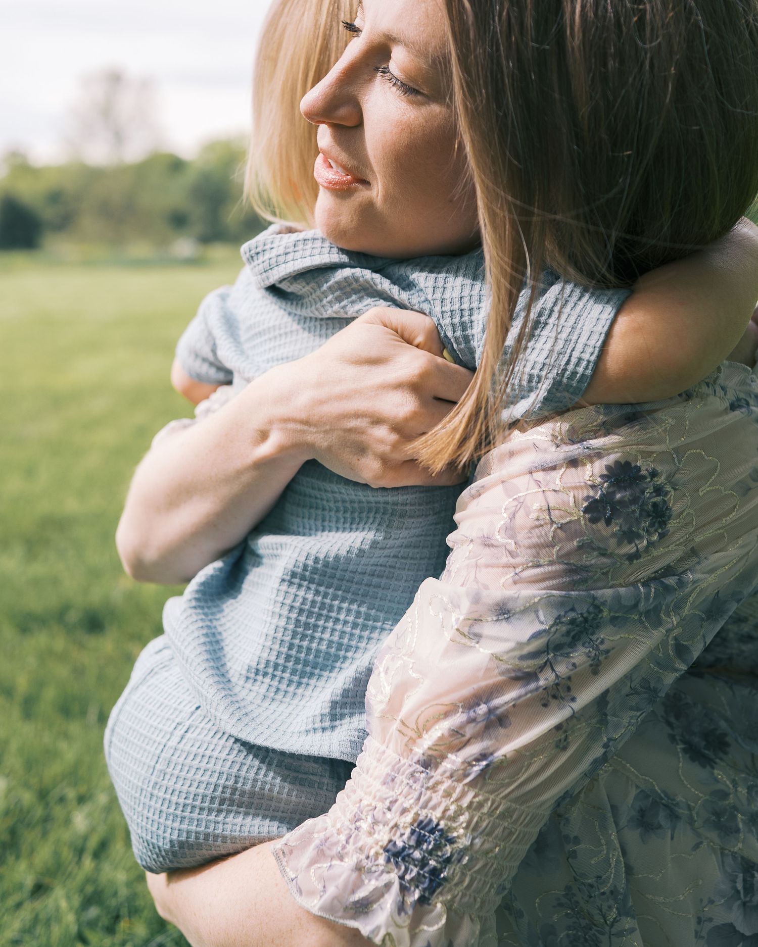 Parents share a tender moment with toddler in casual summer outfits outdoors.