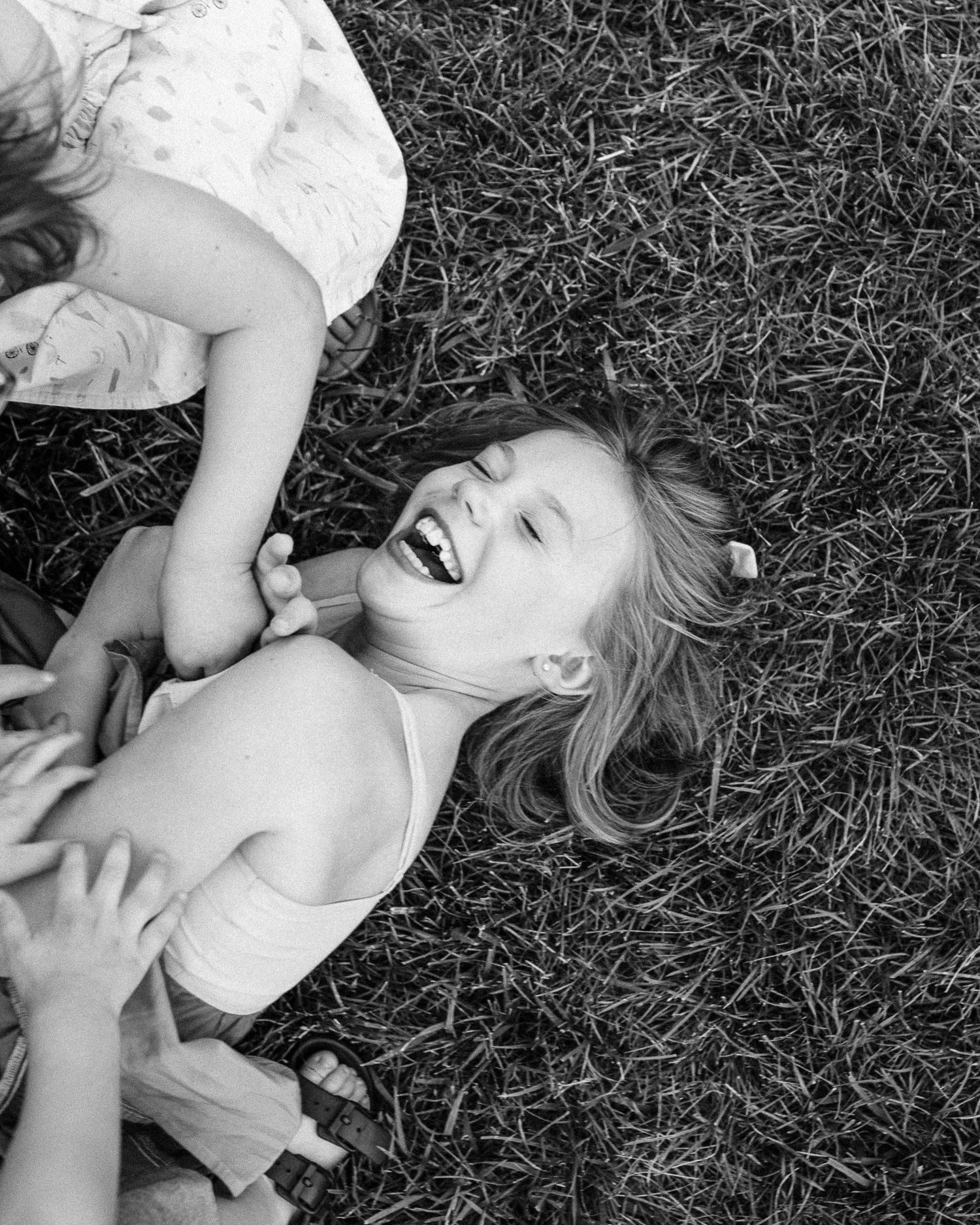 Black and white image of children laughing and playing on grass.