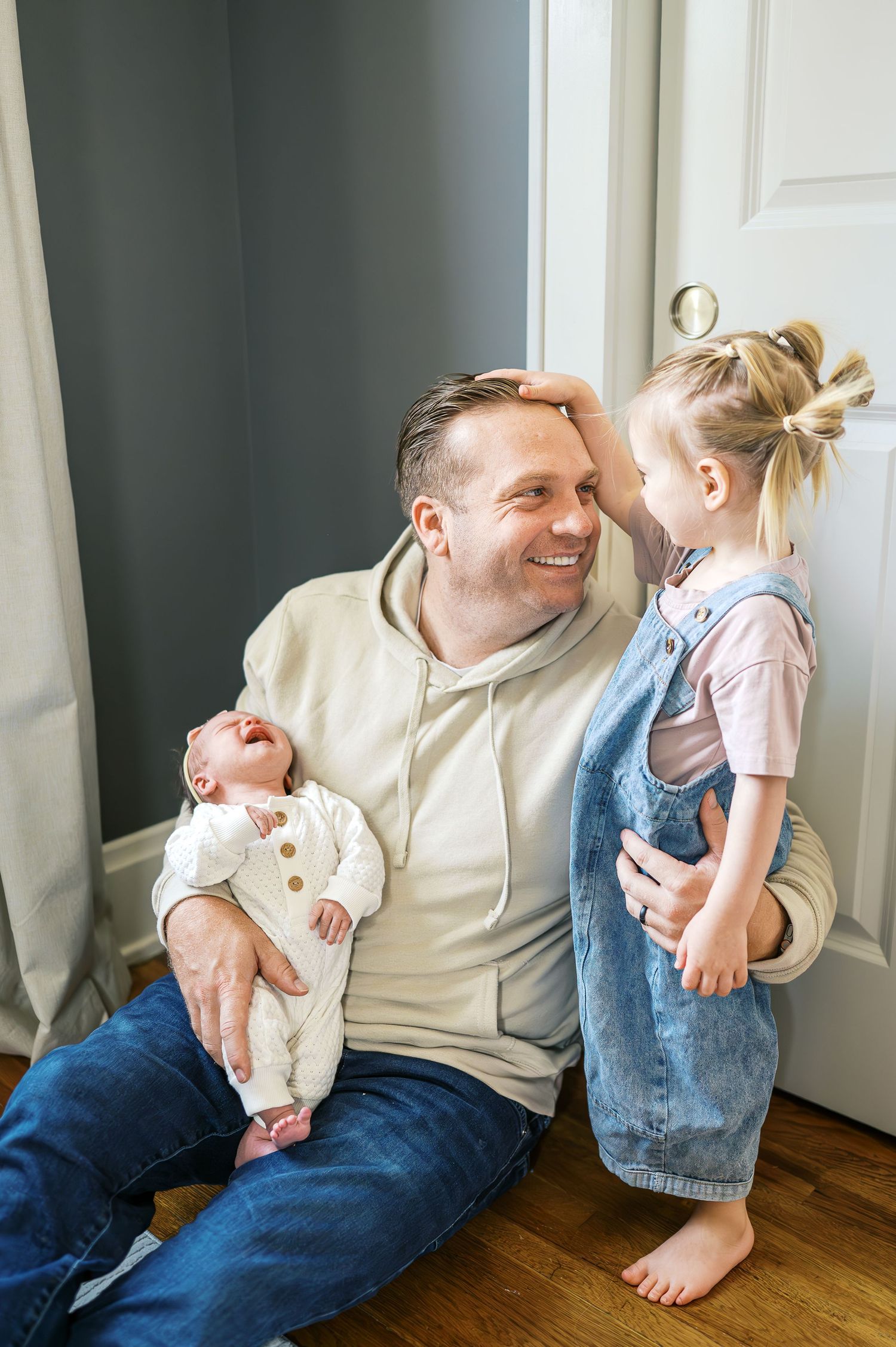 A cheerful family moment shared in front of a white door on hardwood flooring.