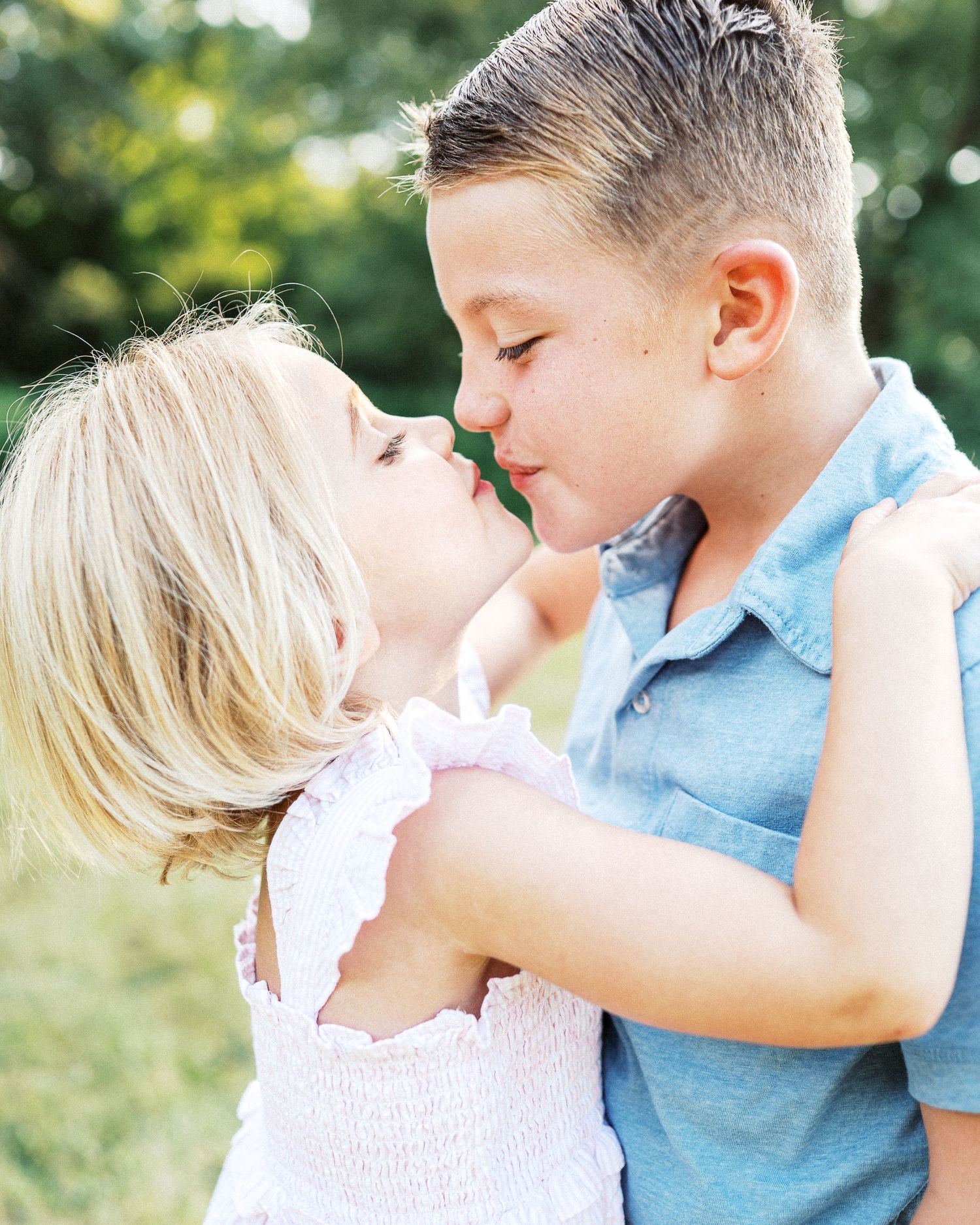 Two children sharing a sweet moment together outdoors in summer.