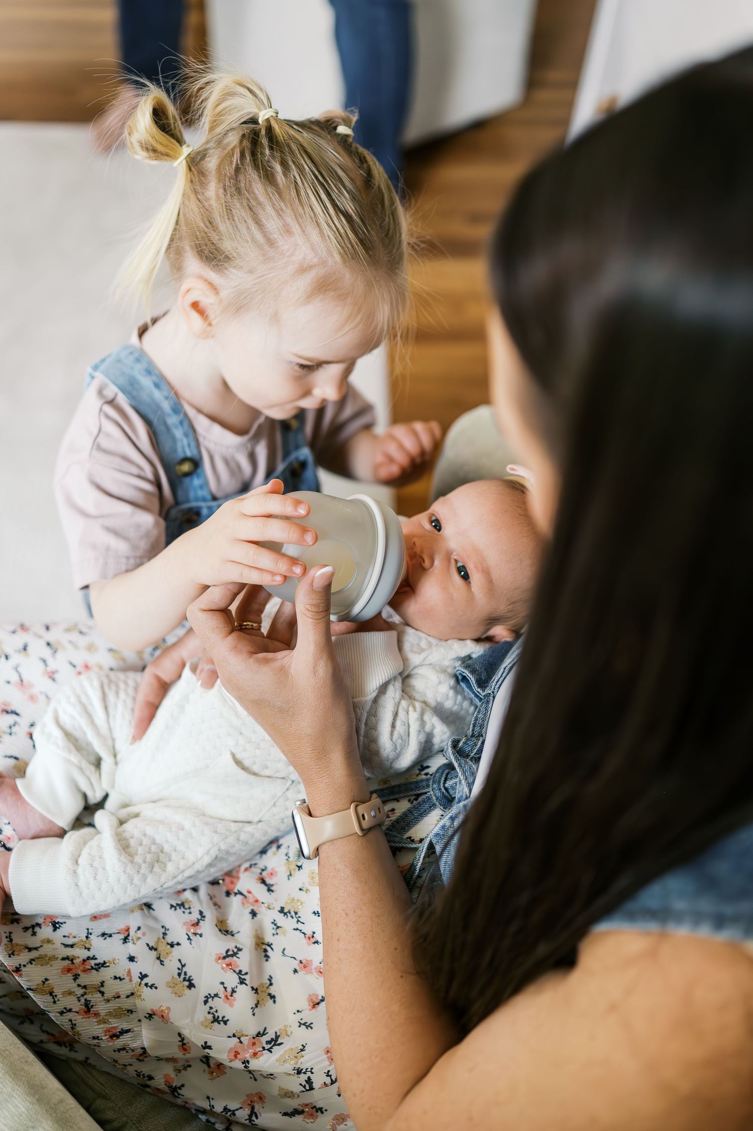 A baby being bottle fed while family members gather close in a tender moment.