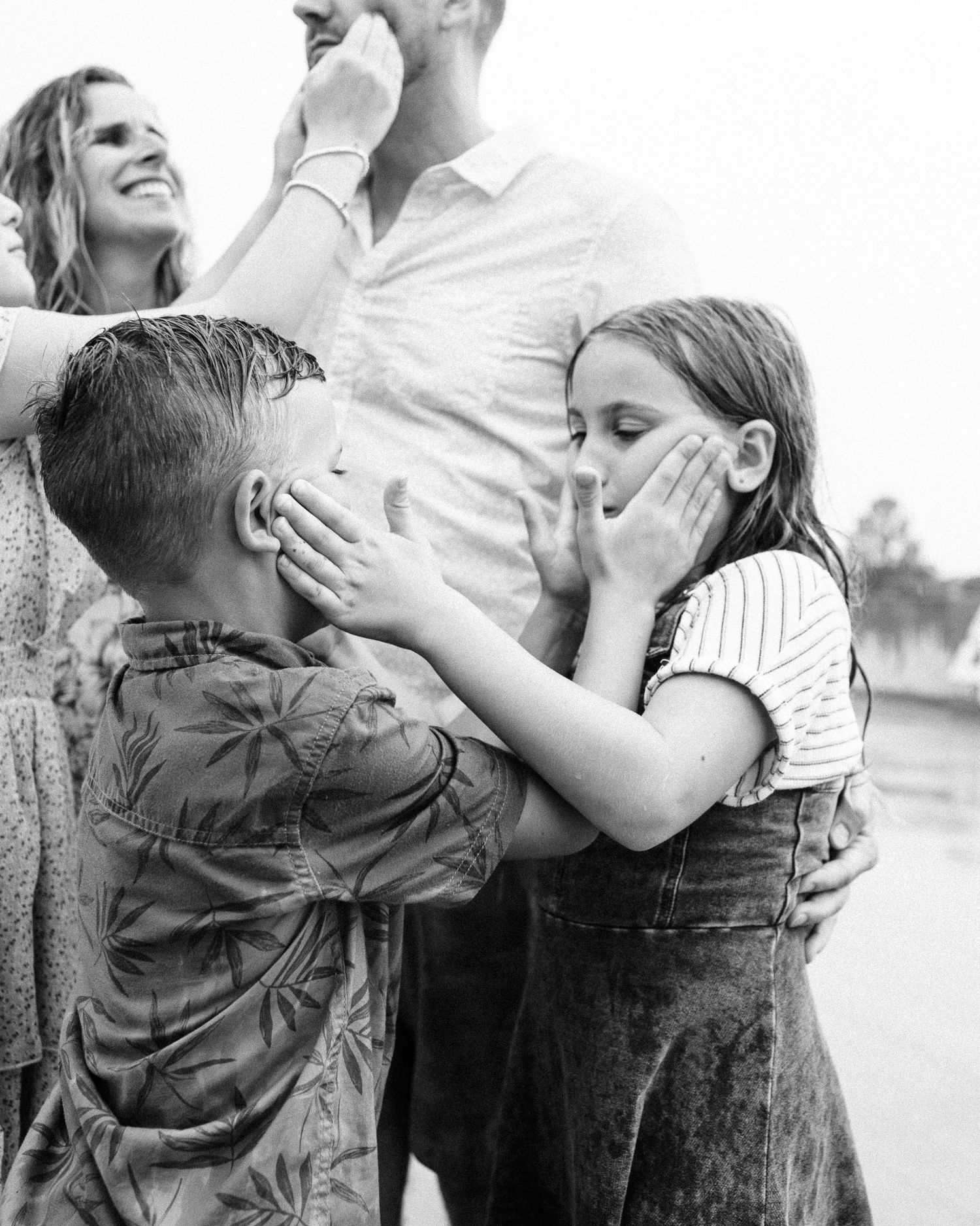 Candid moments of family members hugging and laughing in black and white.