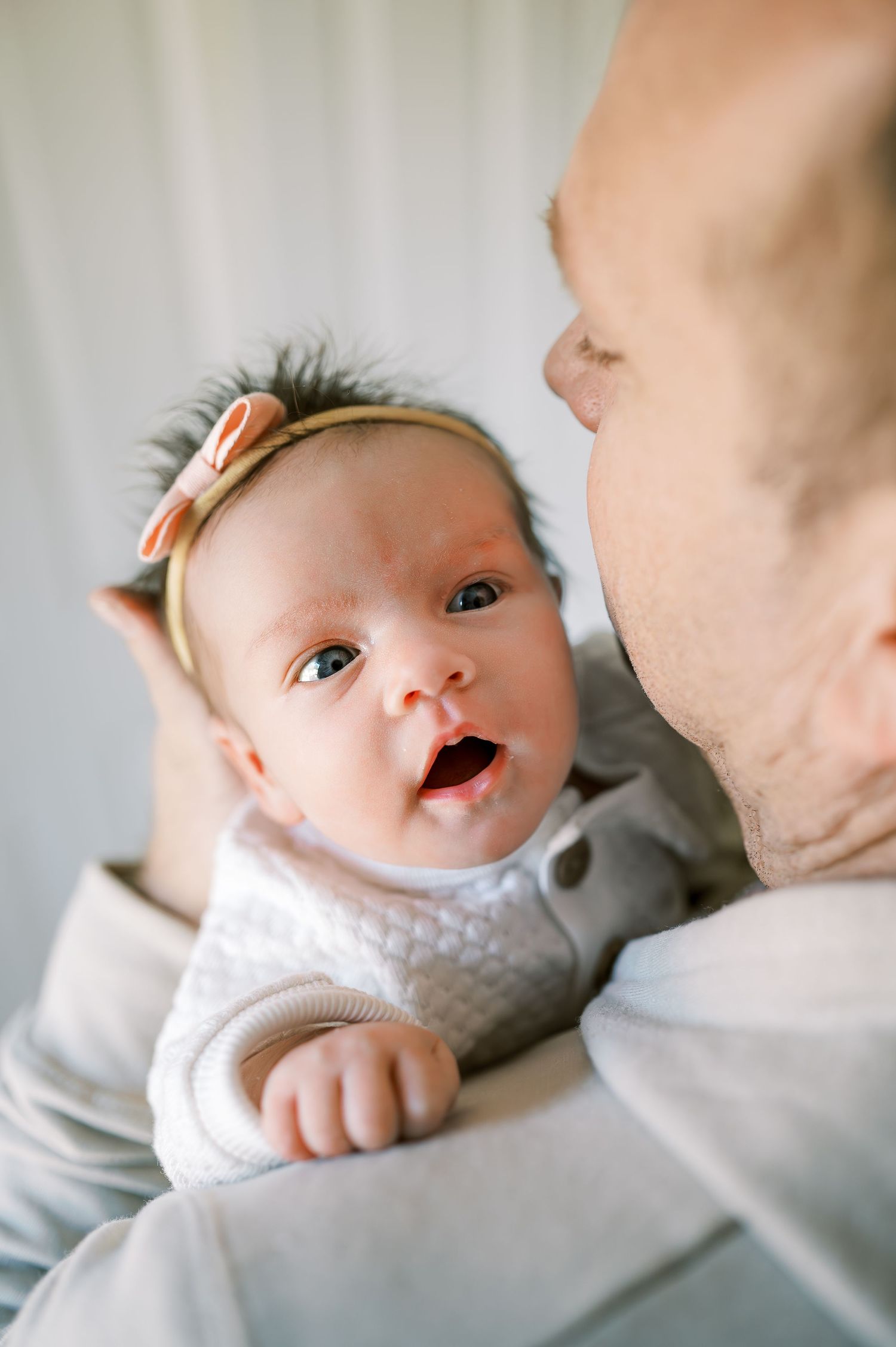 Alert baby wearing headband looks up with wide-eyed expression.
