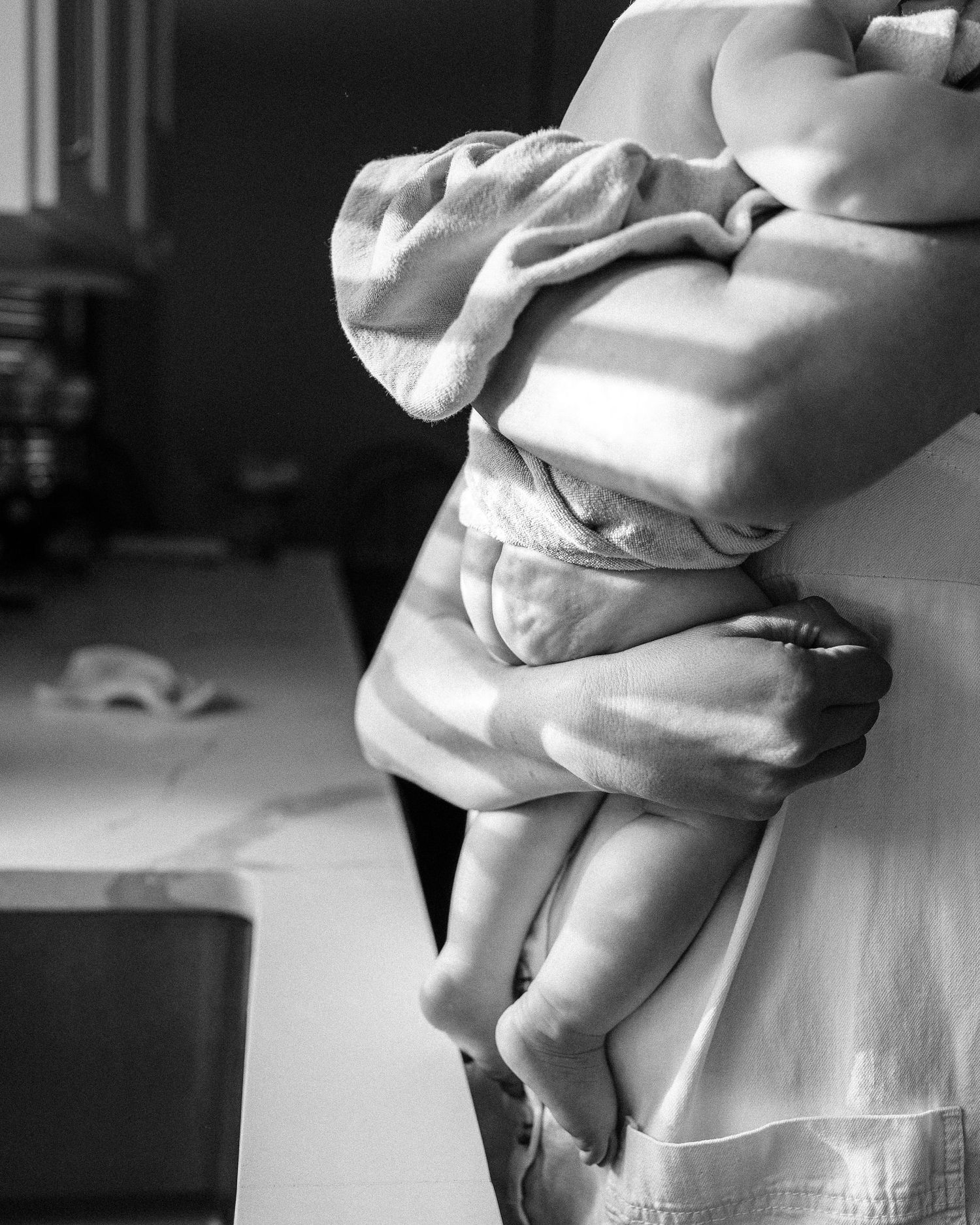 Black and white image of a baby in soft clothing being held close.