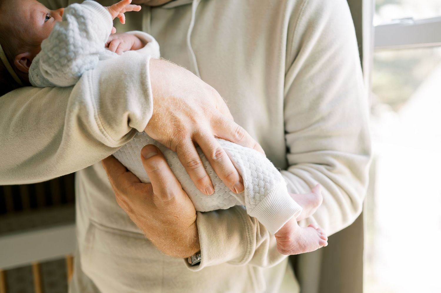 Gentle embrace of a small baby wearing soft white clothing.