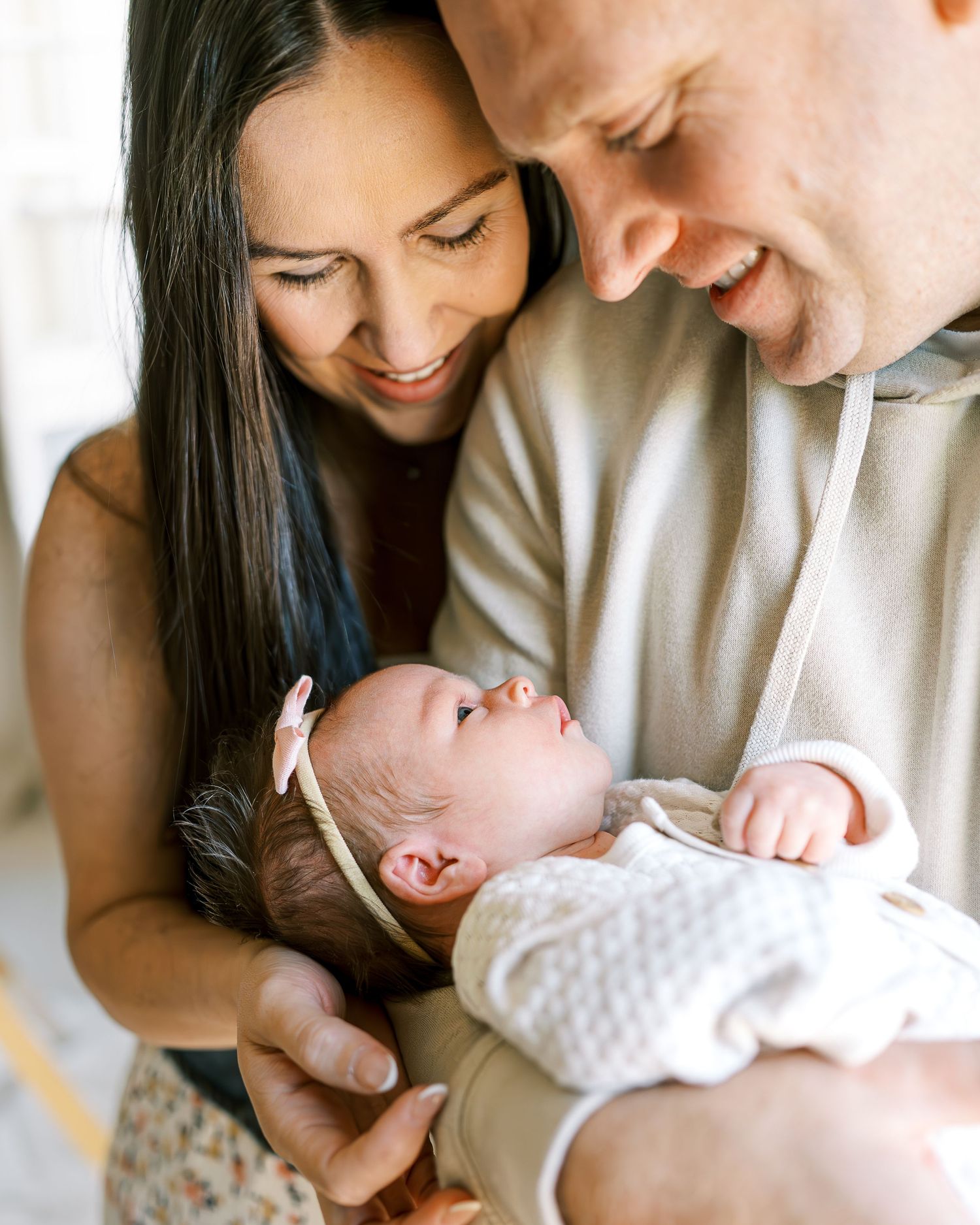 Intimate moment with a newborn baby being held by parents indoors.