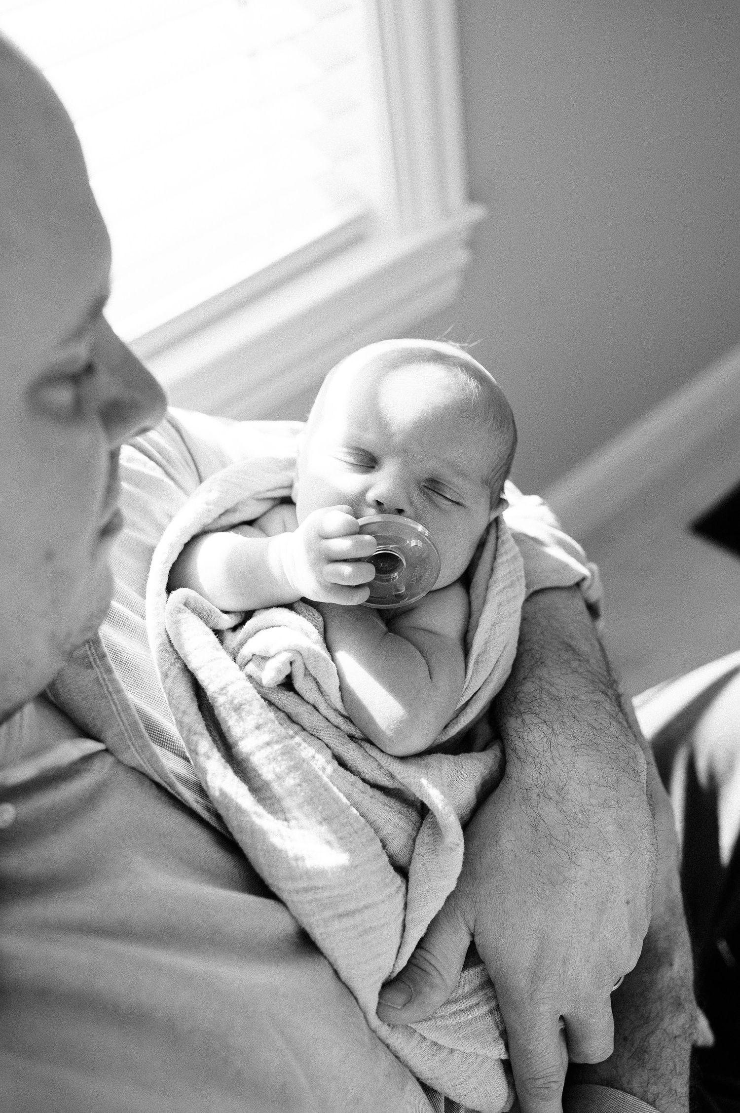 Black and white portrait series of sleeping newborn resting on parent's shoulder.