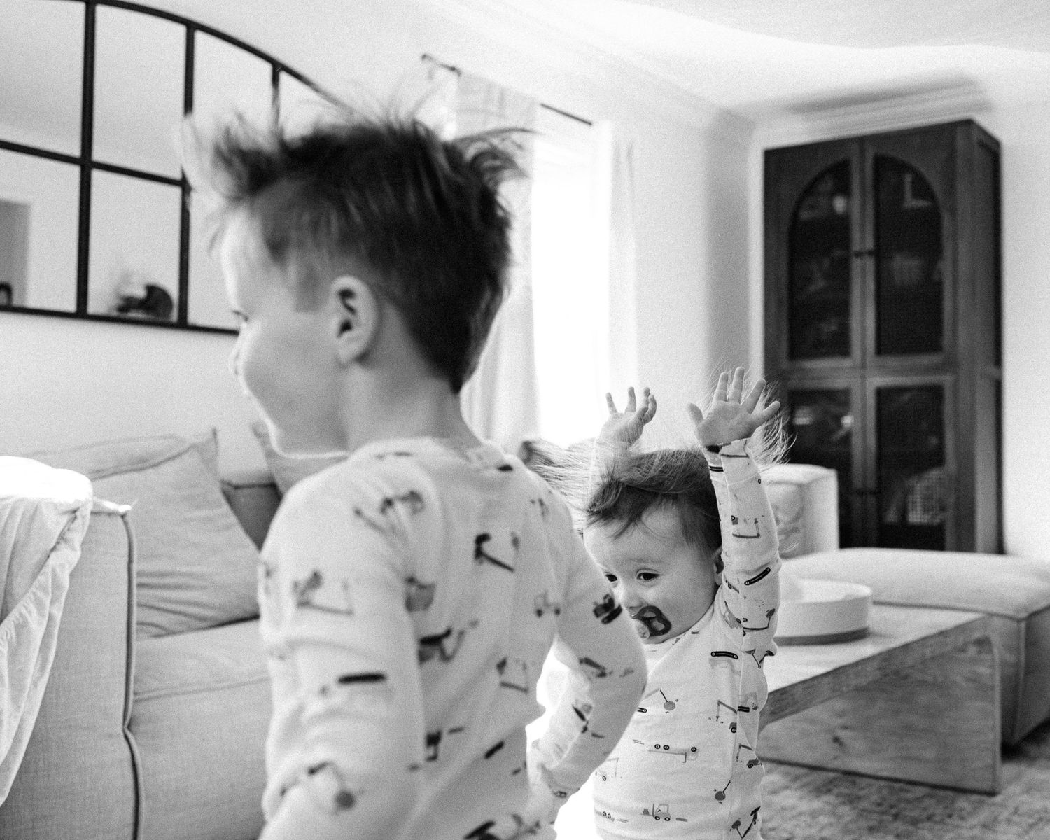 A series of black and white photographs showing playful interaction in a modern home setting.