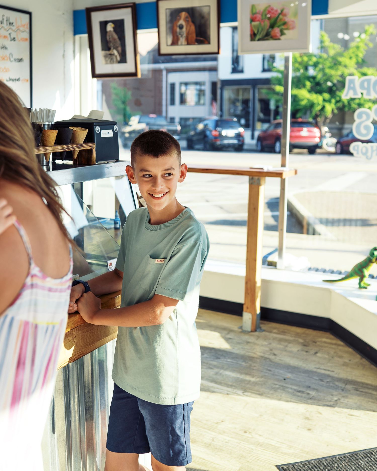 Young customer smiling while ordering at an ice cream shop counter.