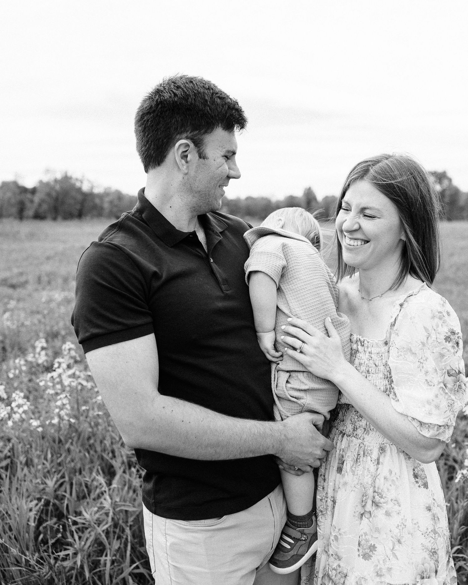 Black and white portrait of a family outdoors in a wildflower field.