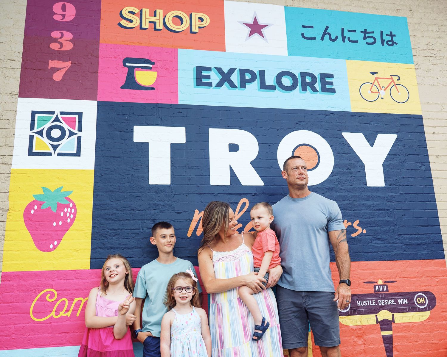 Colorful mural wall with text reading TROY featuring shop and explore graphics.