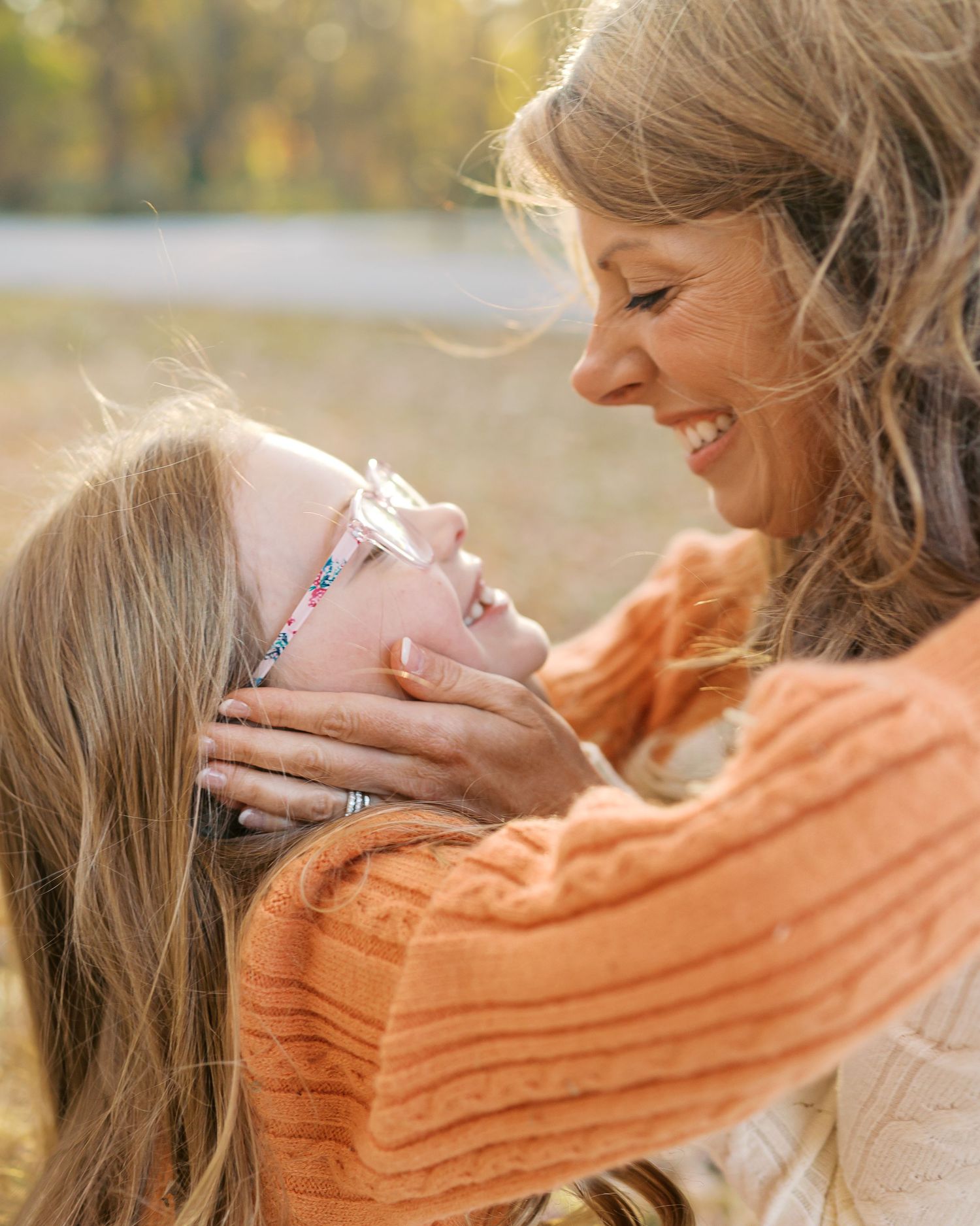 Intimate moment between family members sharing laughter outdoors in autumn setting.