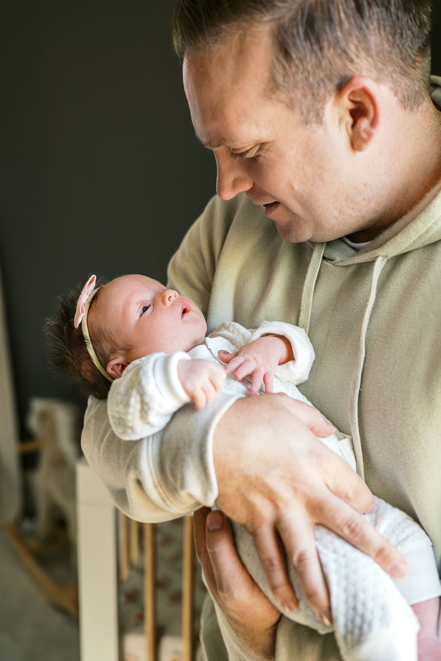 An intimate moment as a baby in white clothing is held carefully and lovingly.