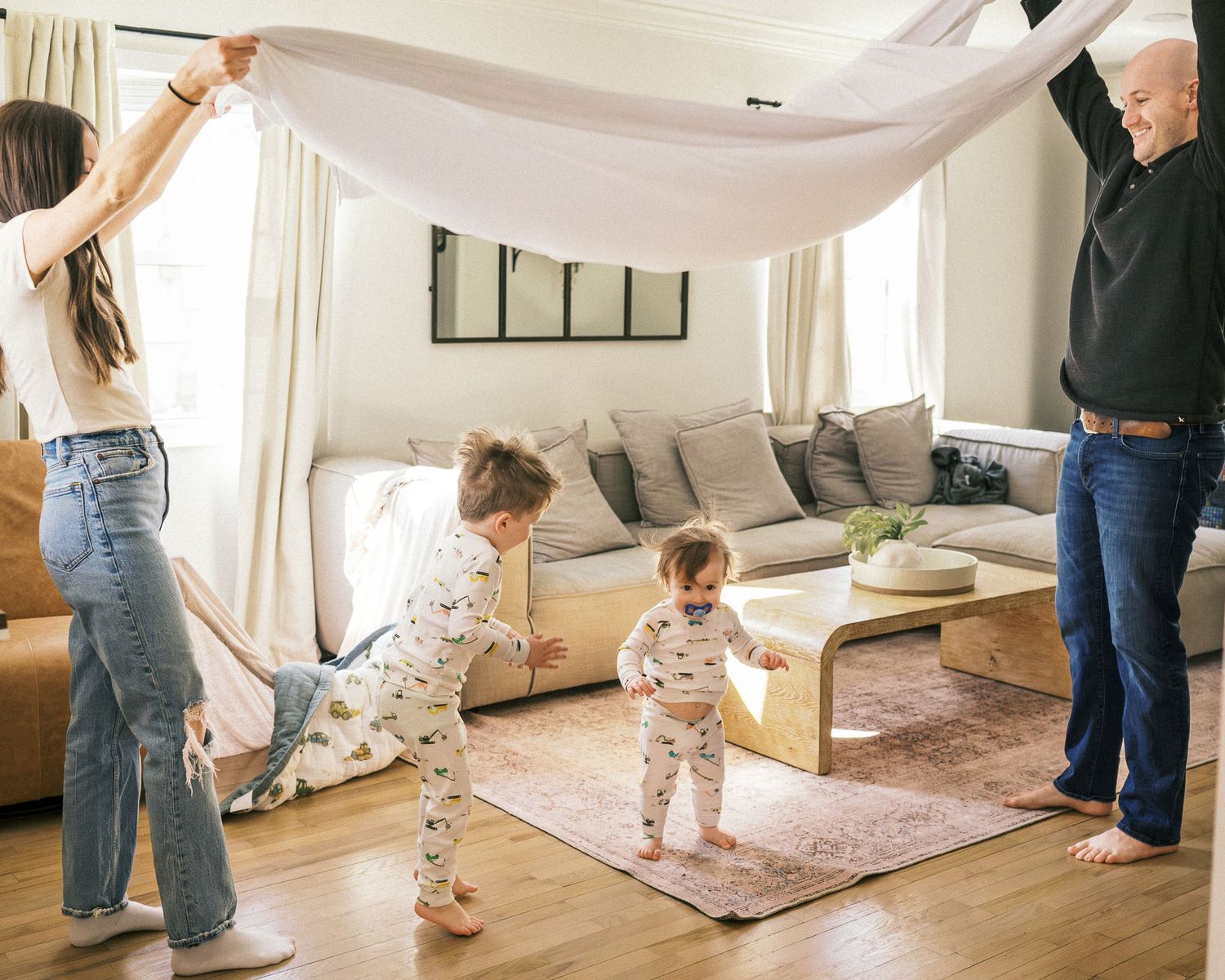 A happy family plays and shares loving moments on a beige area rug in a bright living room.