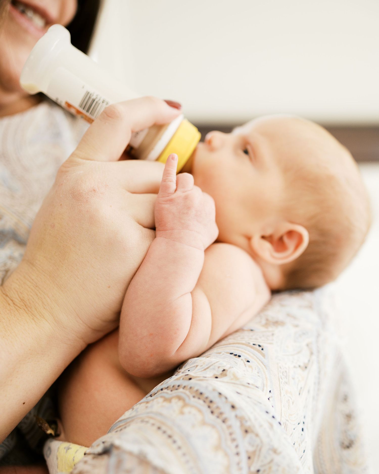 Close-up of feeding time with baby holding bottle.