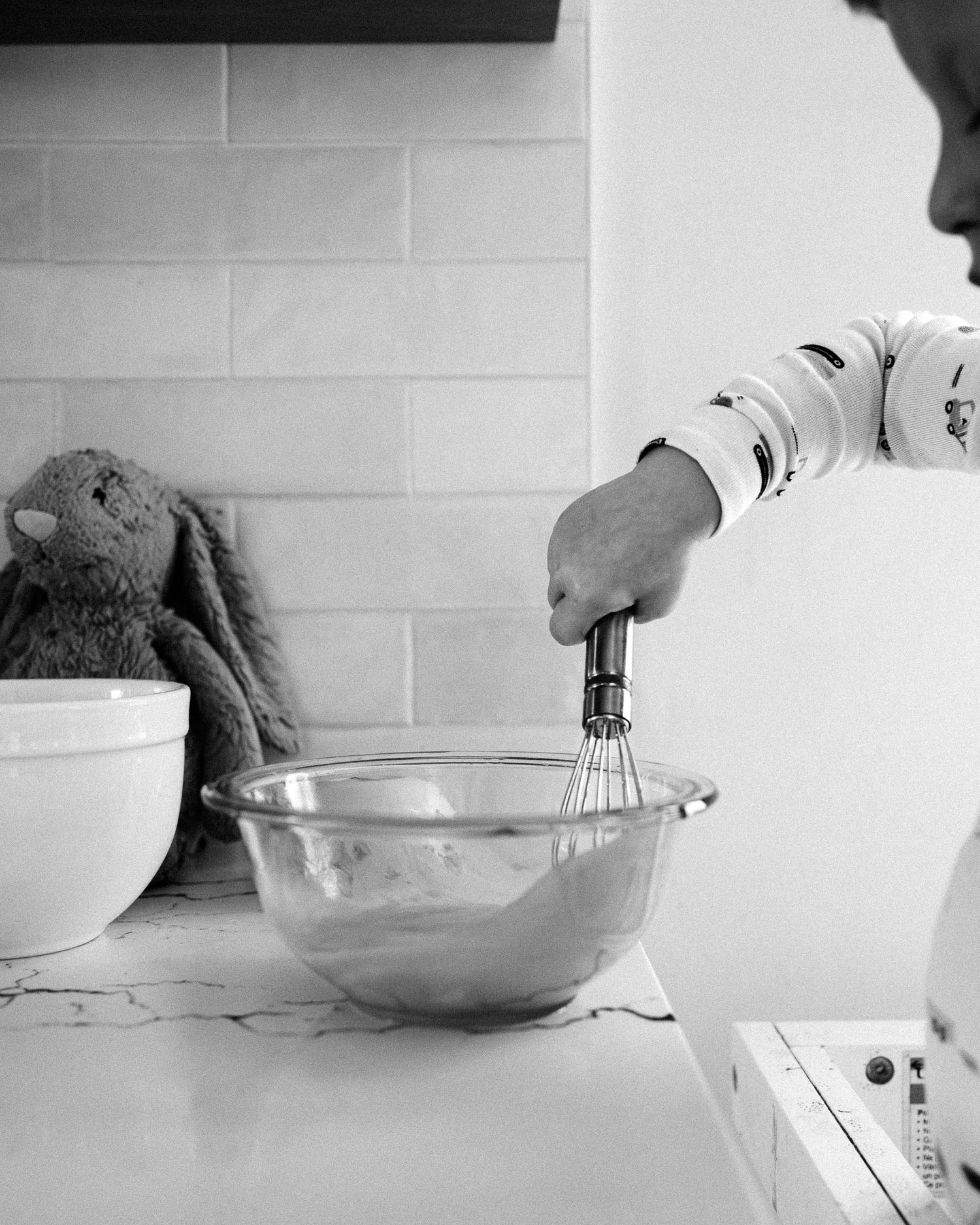Cracking eggs into a clear mixing bowl in a modern kitchen.
