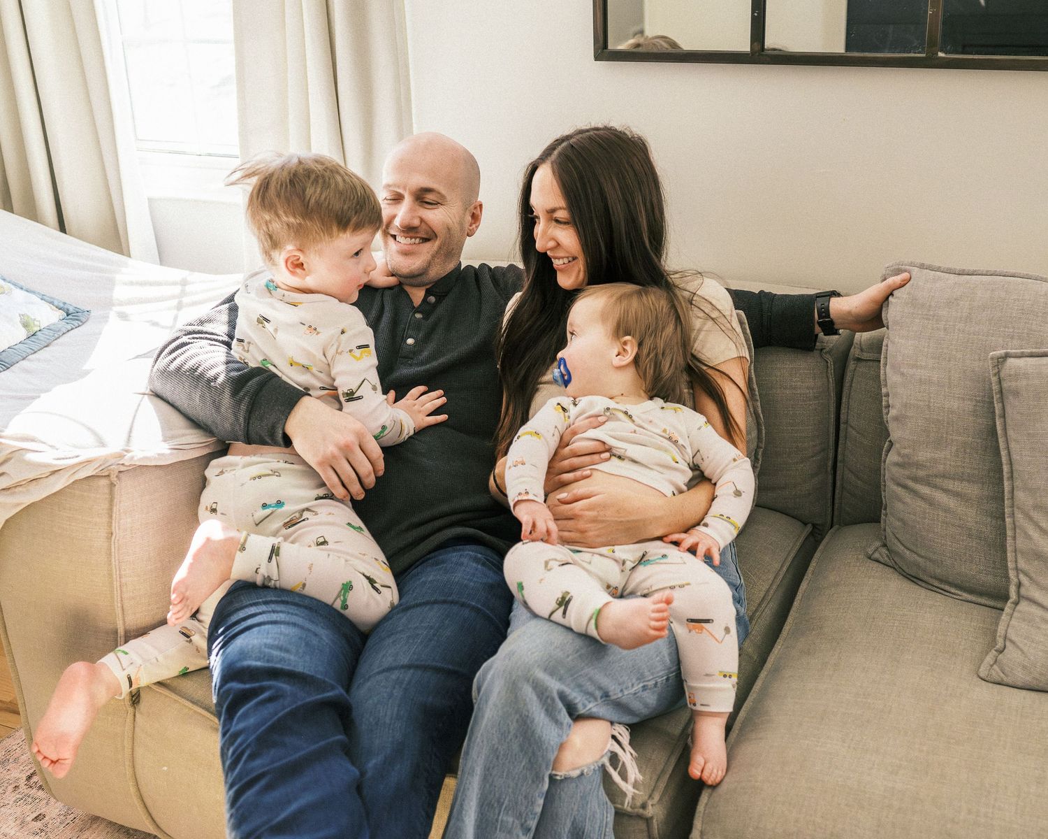 Candid family moment on comfortable gray couch in bright modern living room.